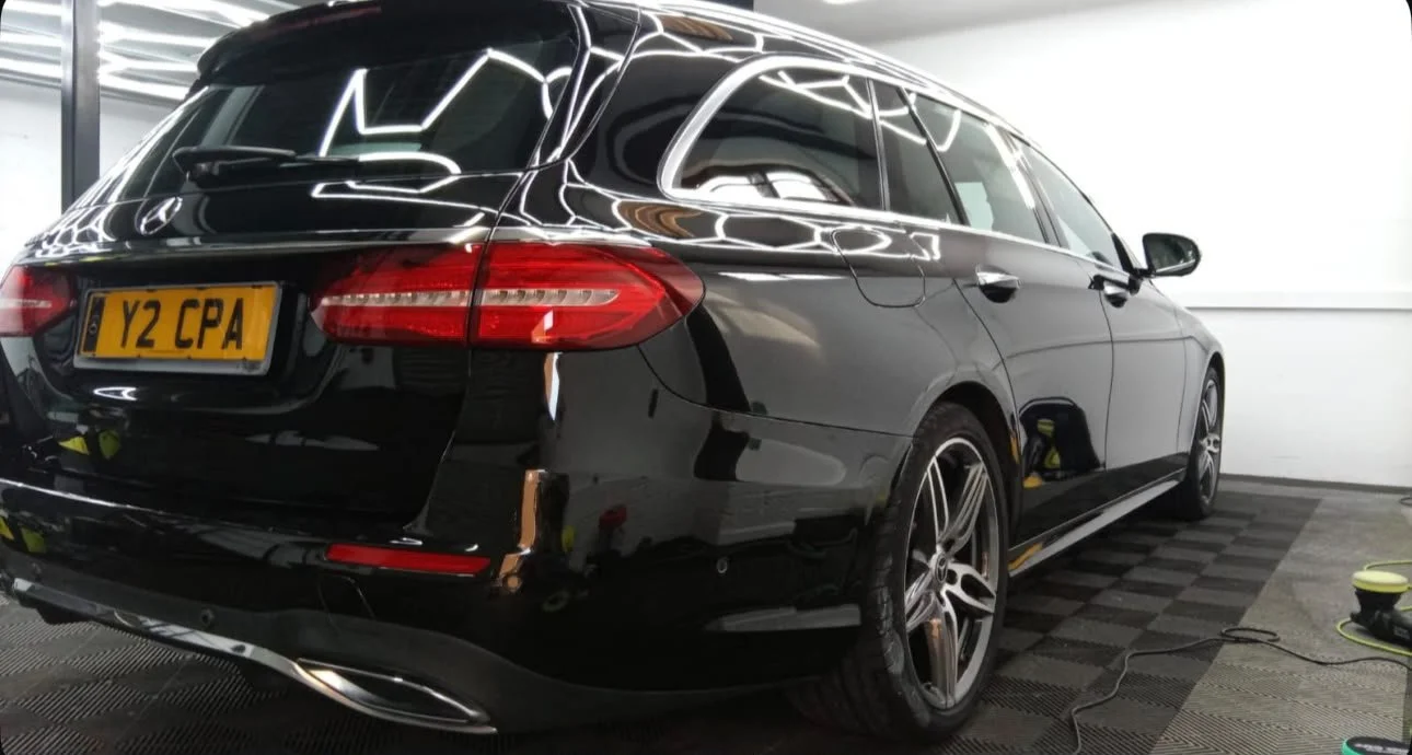 A black Mercedes-Benz station wagon in a garage, with a U.S. license plate reading 'Y2 CPA'.
