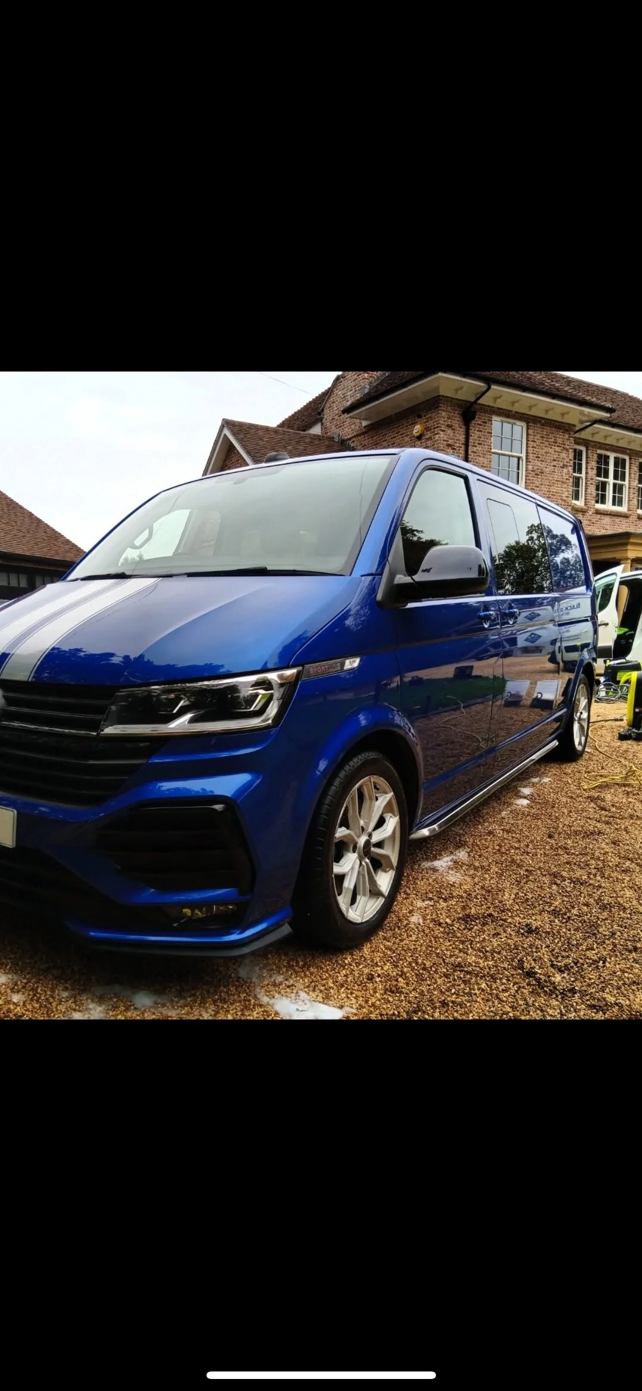Blue Volkswagen van parked on gravel driveway in front of house