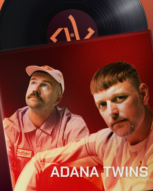 Two men with styled hair and facial hair, one wearing a striped pink shirt and a white cap, and the other wearing a yellow shirt, posing in front of a red background with a record and a code symbol on the wall behind them. The text 'ADANA TWINS' is displayed at the bottom.