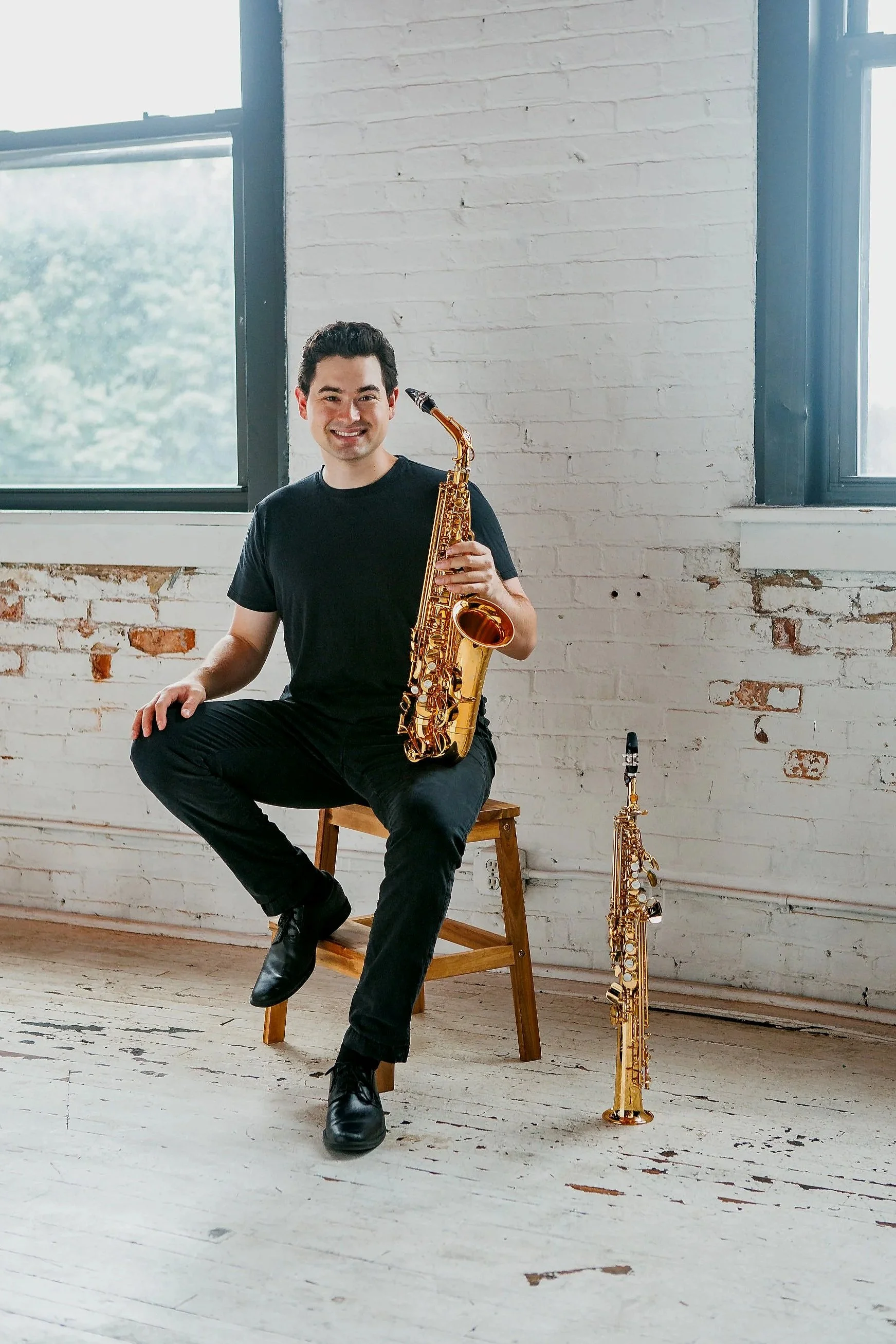 Landon Chang, saxophone professor and multi-instrumentalist, posing with alto and soprano saxophones in a bright Rochester studio