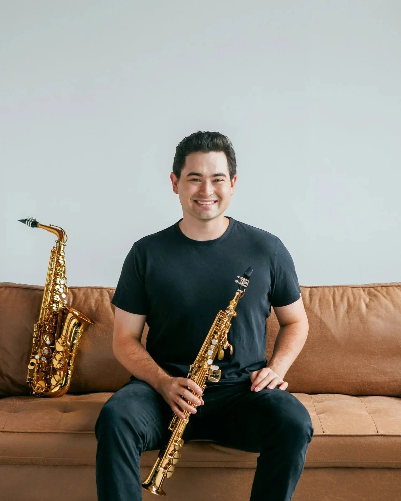 Landon Chang, saxophone professor and multi-instrumentalist, holding a soprano saxophone with an alto saxophone in a professional headshot
