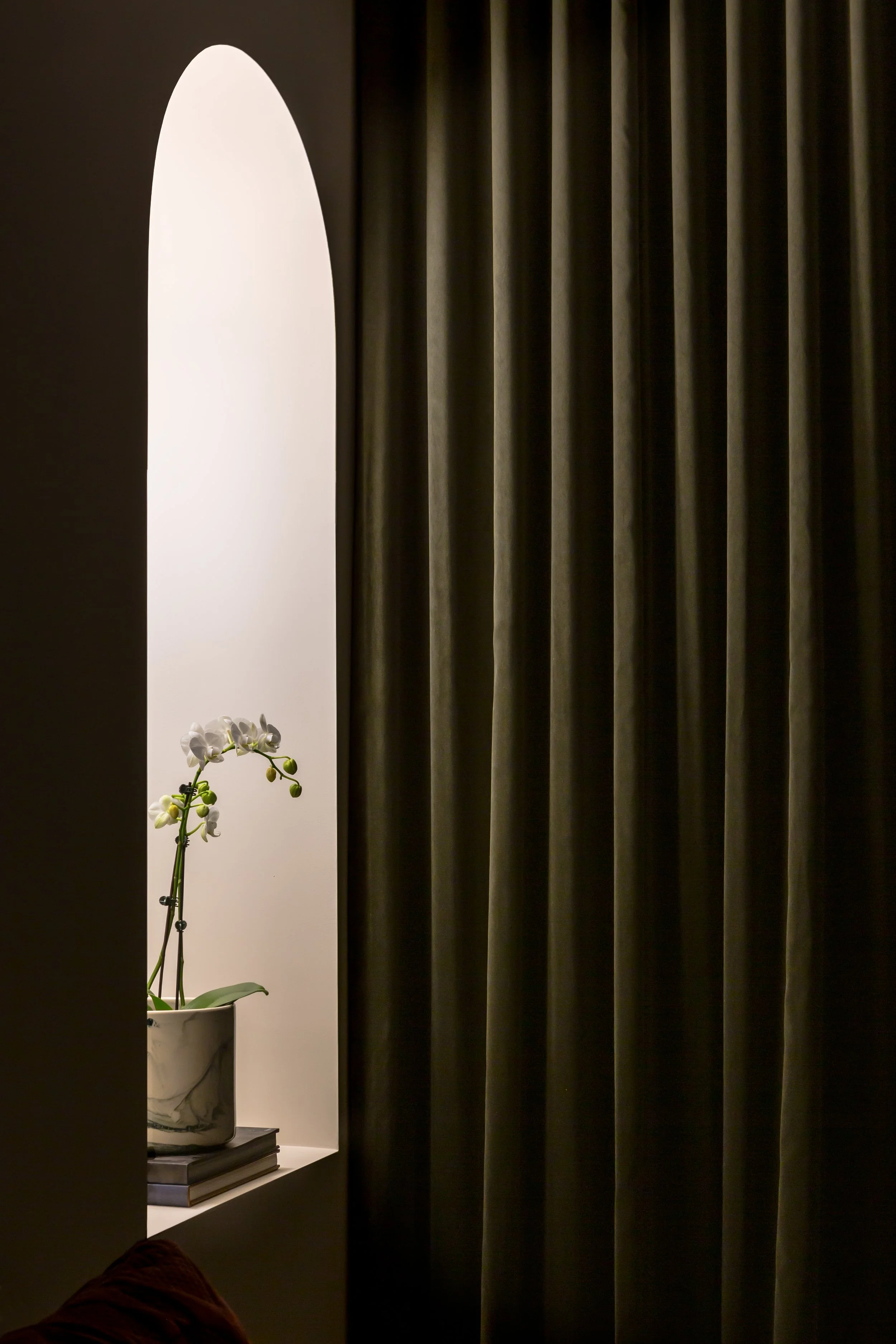 Des rideaux verts et une orchidée à l’intérieur d’un restaurant.