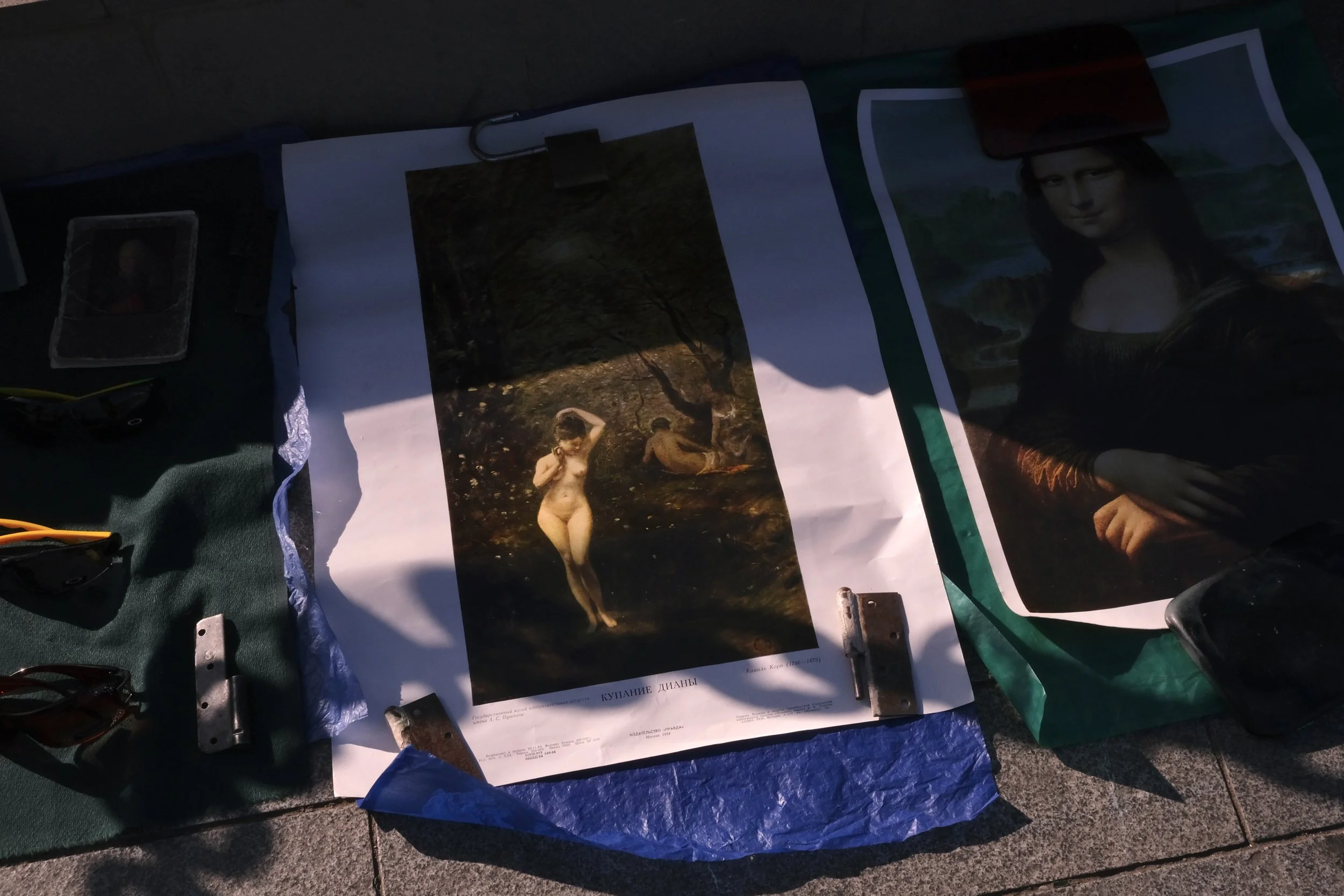 Photograph of a poster featuring a famous painting, with other images and objects laid out on a surface.