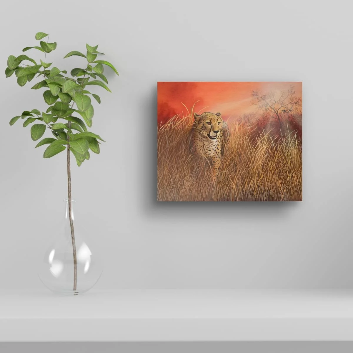 Painting of a cheetah walking through tall grass with an orange and pink sunset background, placed on a light gray wall.
