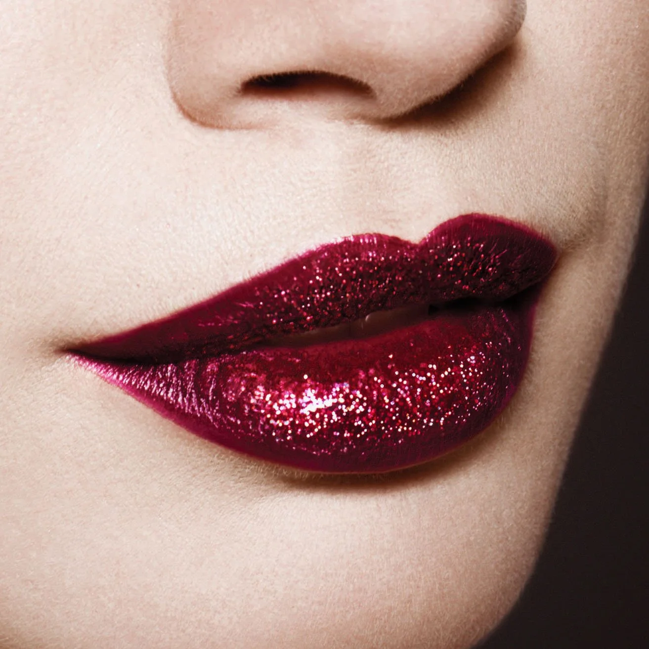 Close-up of a person's lips with deep red, glittery lipstick.