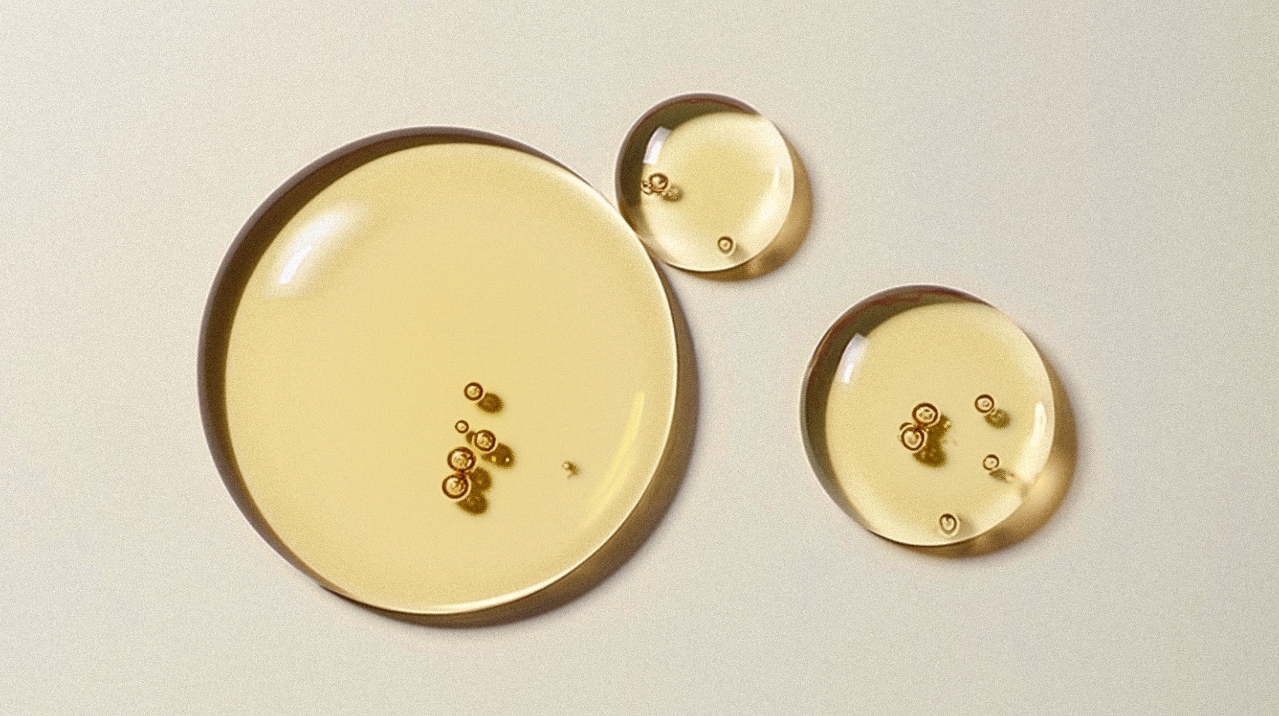 Three tea light candles with small flames, placed on a plain surface.