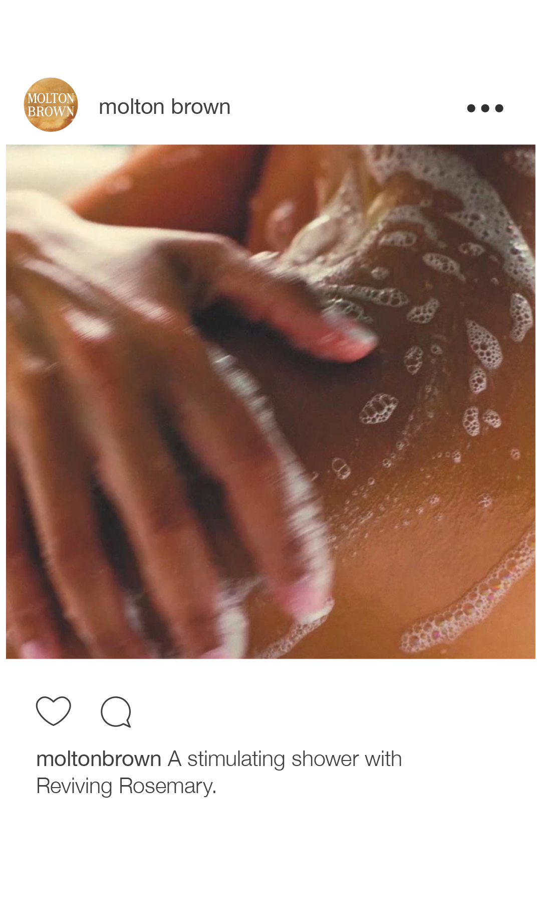 Close-up of a person's back with a hand massaging or applying soap, with soap bubbles visible in the shower.