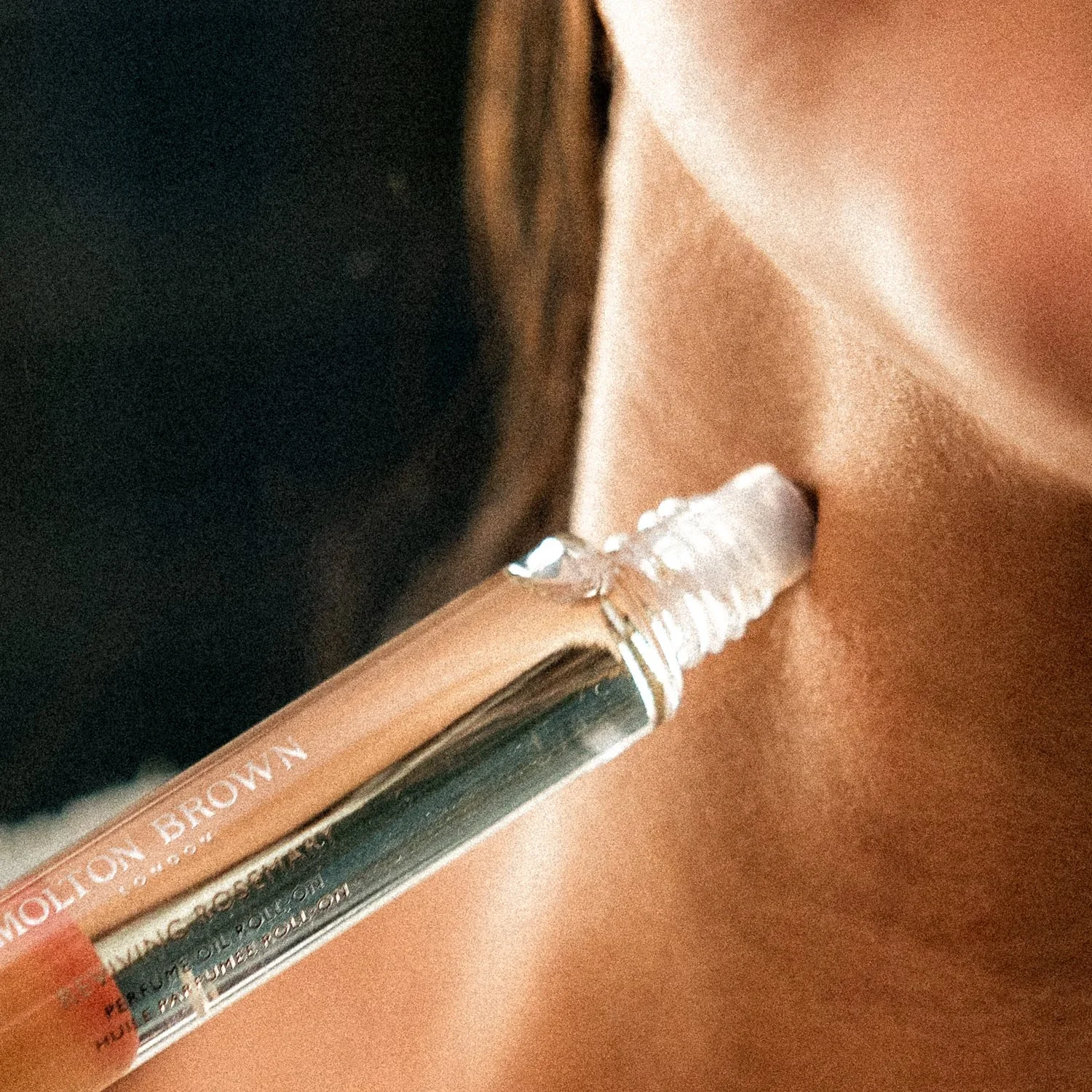 A cosmetic applicator being used on a person's neck, close-up of the person's face and the applicator.
