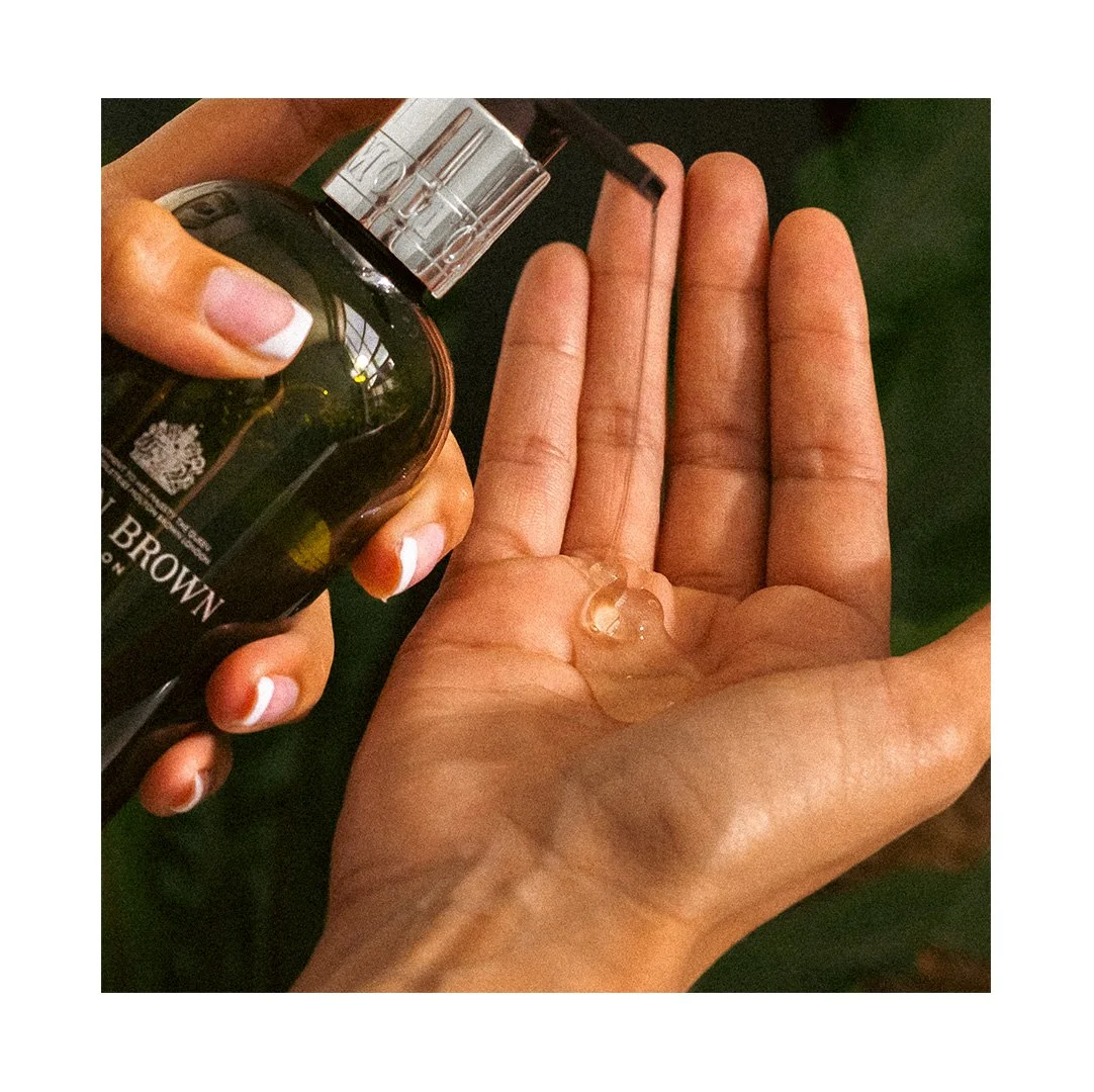 A person is pouring skincare or cosmetic product from a bottle onto their palm.