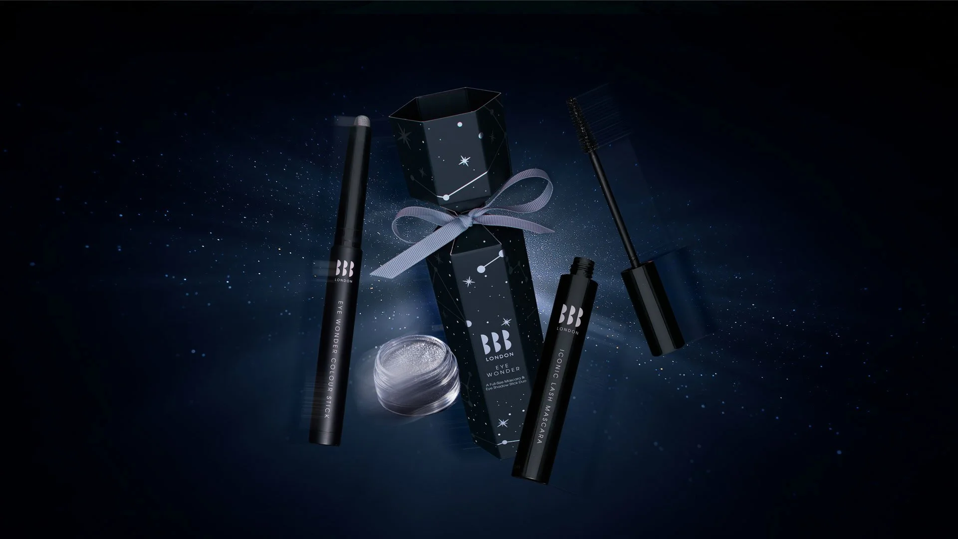 Beauty products including an eye pencil, mascara, eye gel, and an eye mask, with a starry night background and a gift box tied with a silver ribbon.