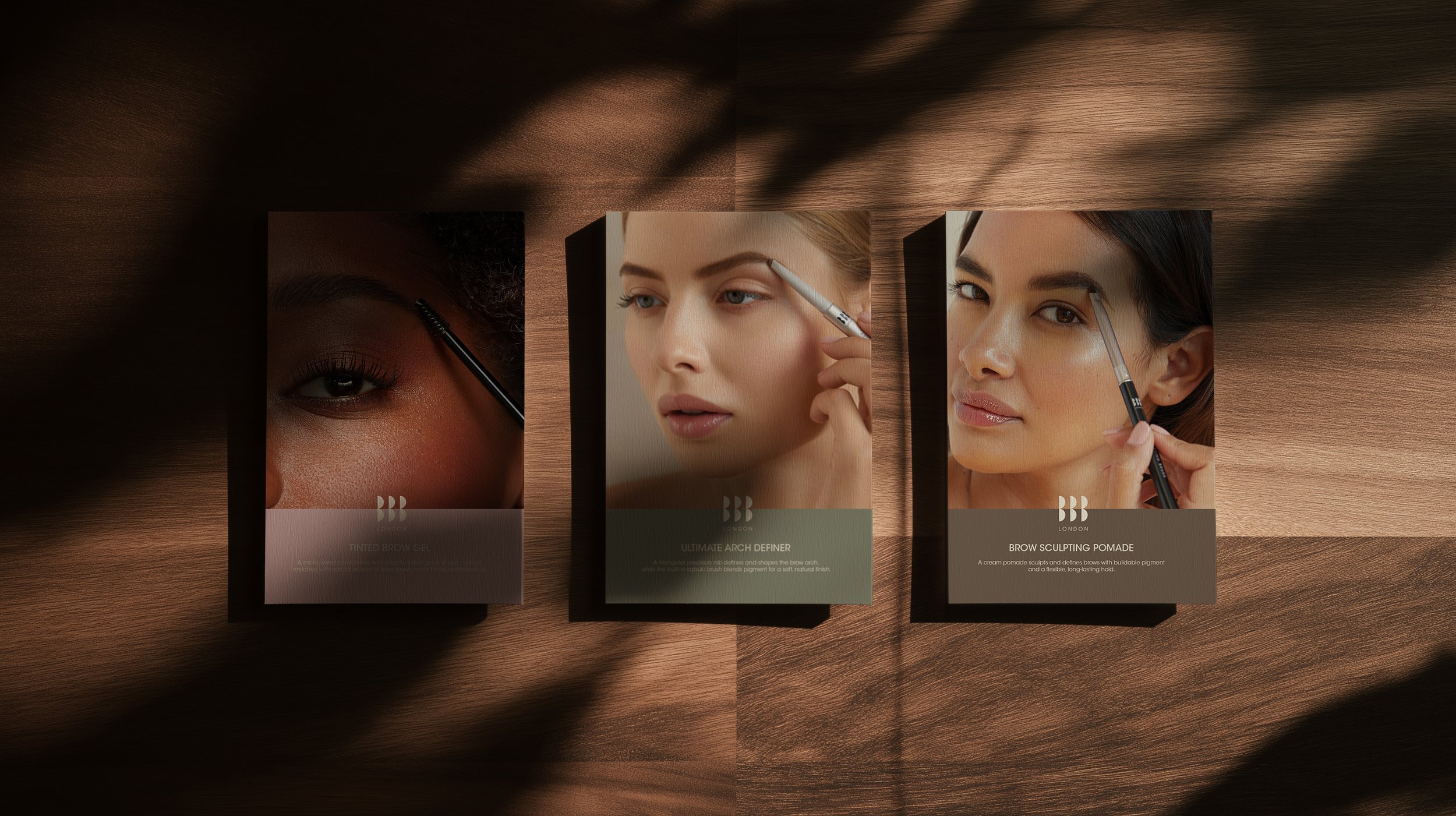 Three brow product cards on a wooden surface, each featuring a woman applying eyebrow makeup, with names 'Tinted Brow Gel,' 'Ultimate Arch Define,' and 'Brow Sculpting Pomade'.