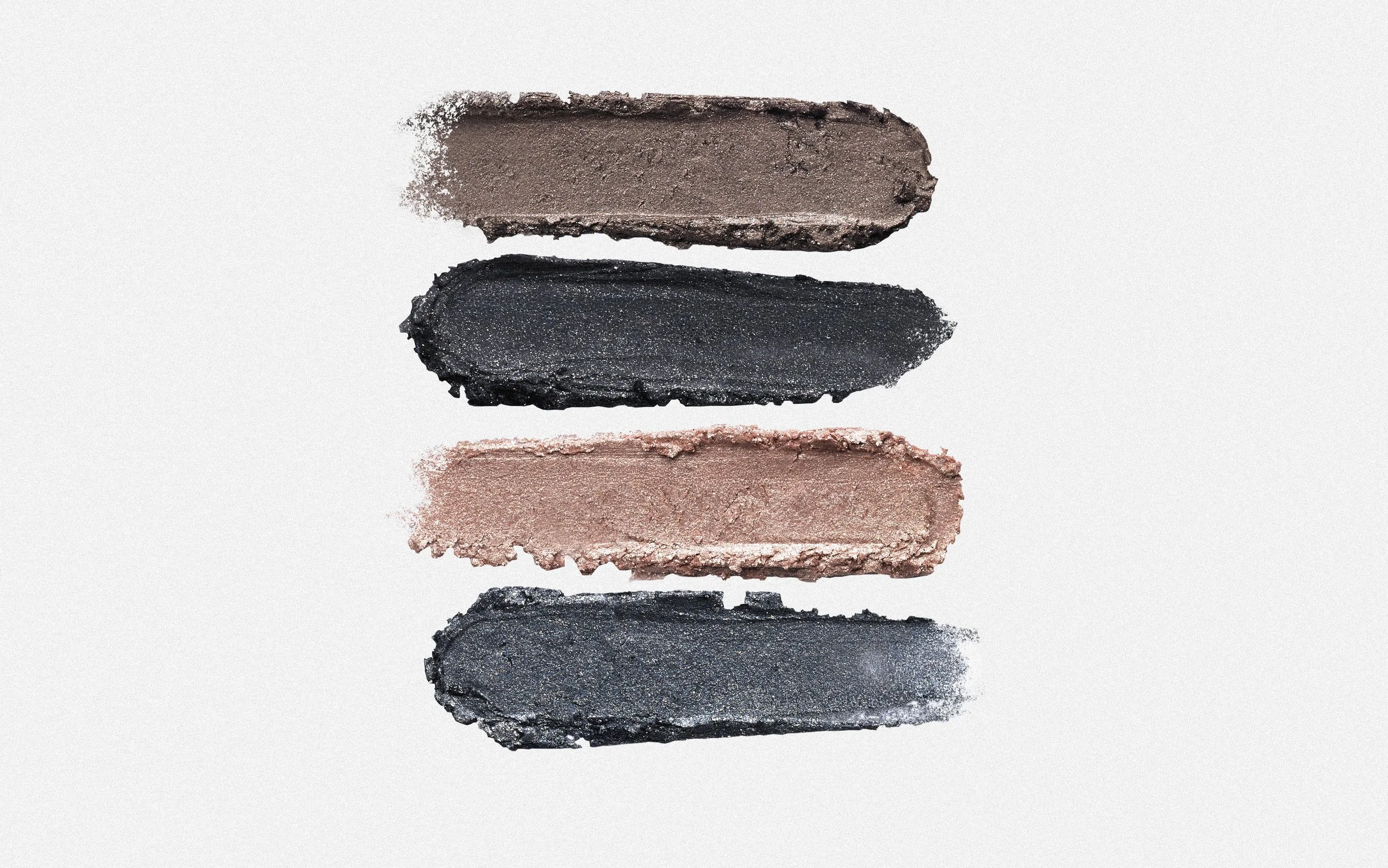 Five swatches of makeup eyeshadow arranged vertically on a white background, showing colors from dark brown to black, to light pink.