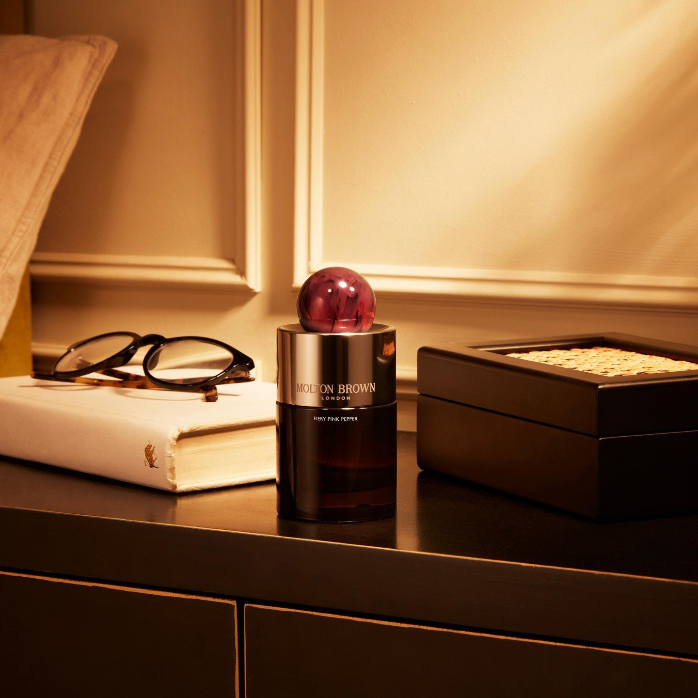 Alt: Styled fragrance products displayed on dresser in warm lifestyle setting