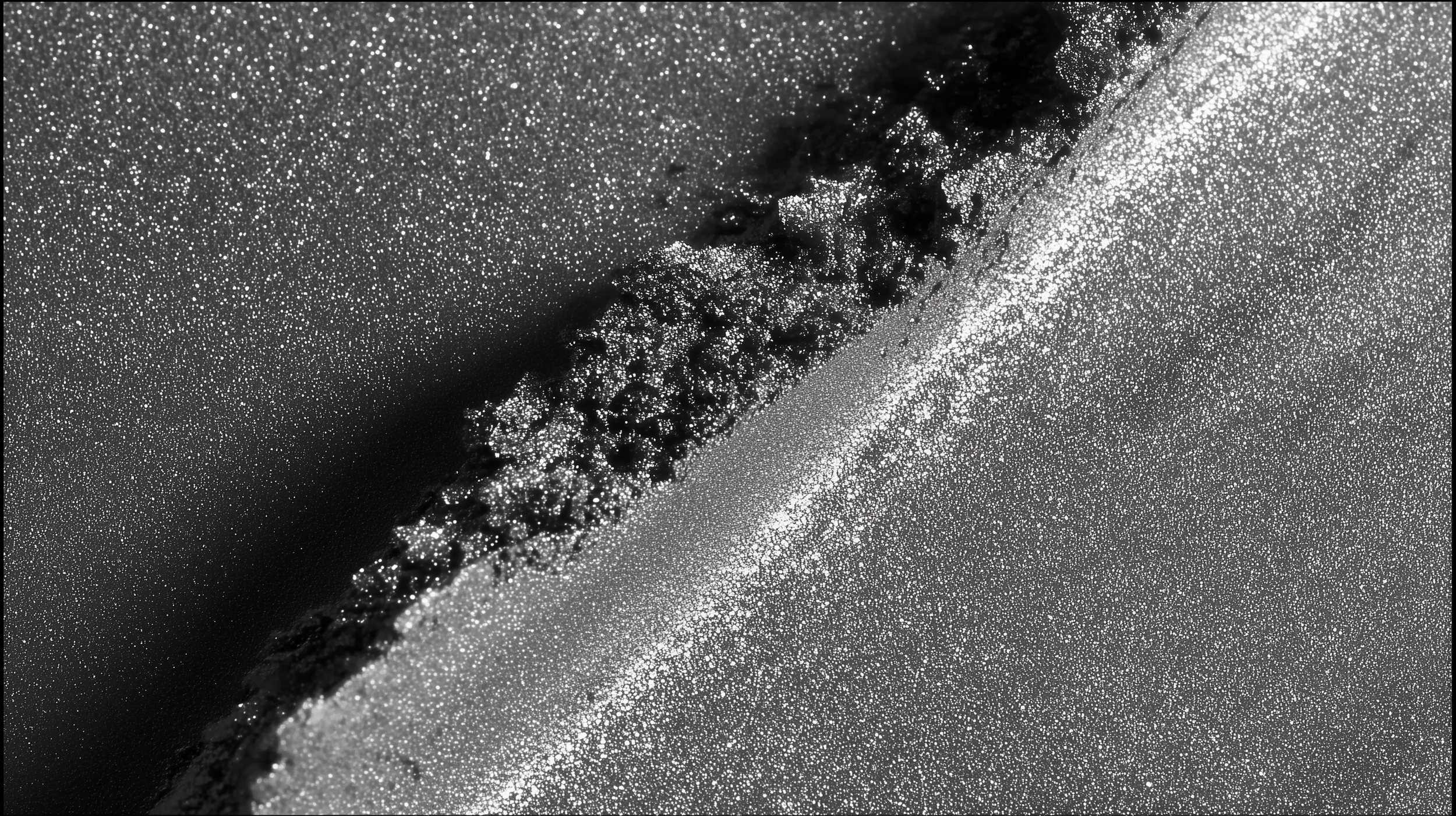 Close-up of black and silver glitter particles on a surface, showing textured patterns and sparkle.