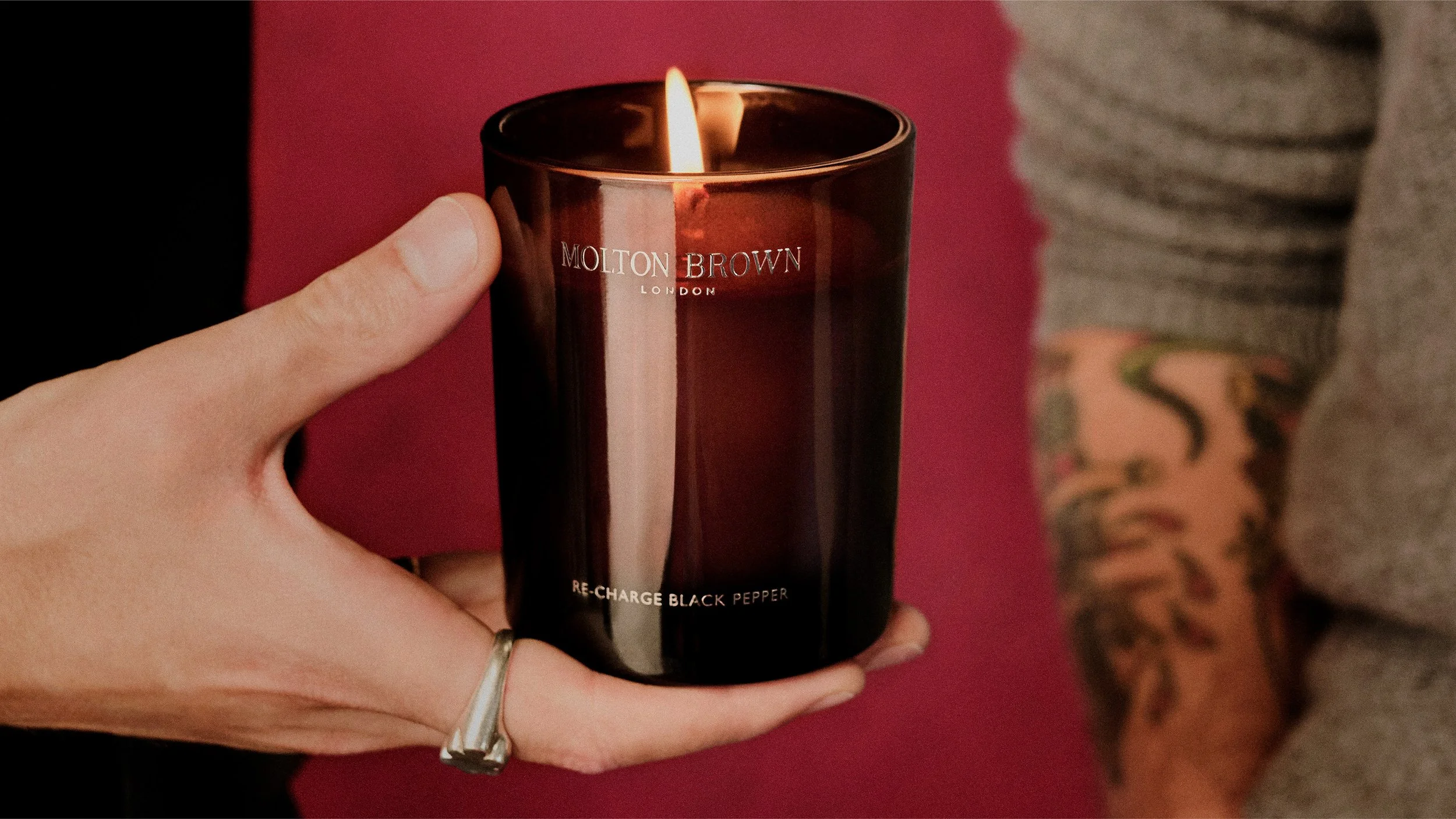 Lit Molton Brown candle beauty still from Christmas gifting campaign, emphasising warmth, mood and gifting desirability.