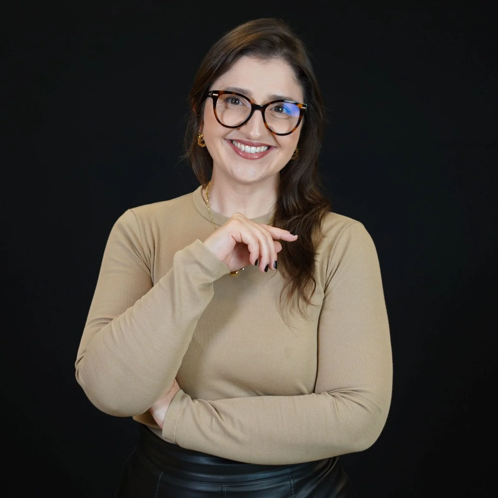 Mulher sorridente com roupa formal cinza e cabelo castanho escuro liso sobre fundo cinza