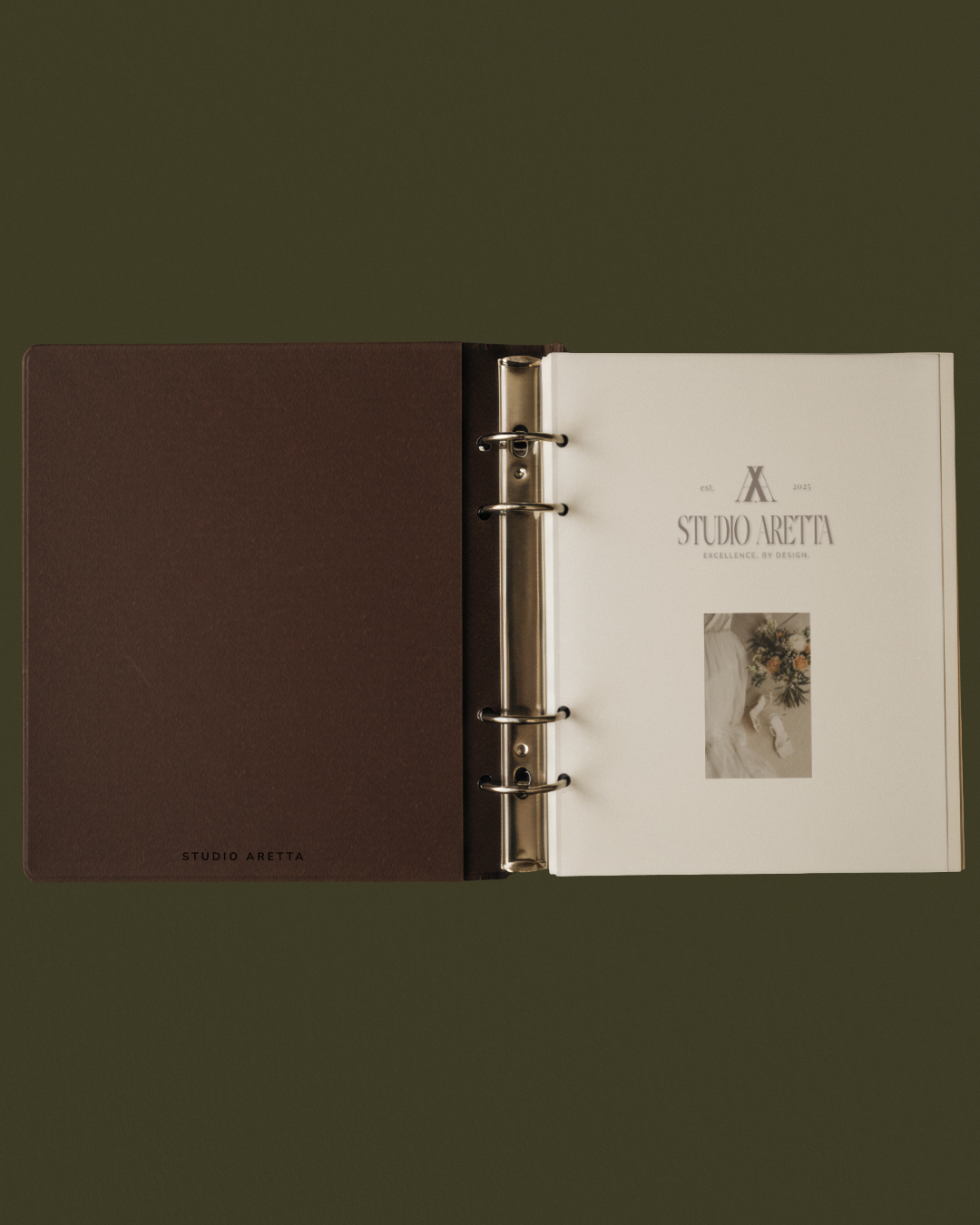 Open binder or photo album with a dark brown cover on the left and a white page on the right, featuring text and an image, on a green background.