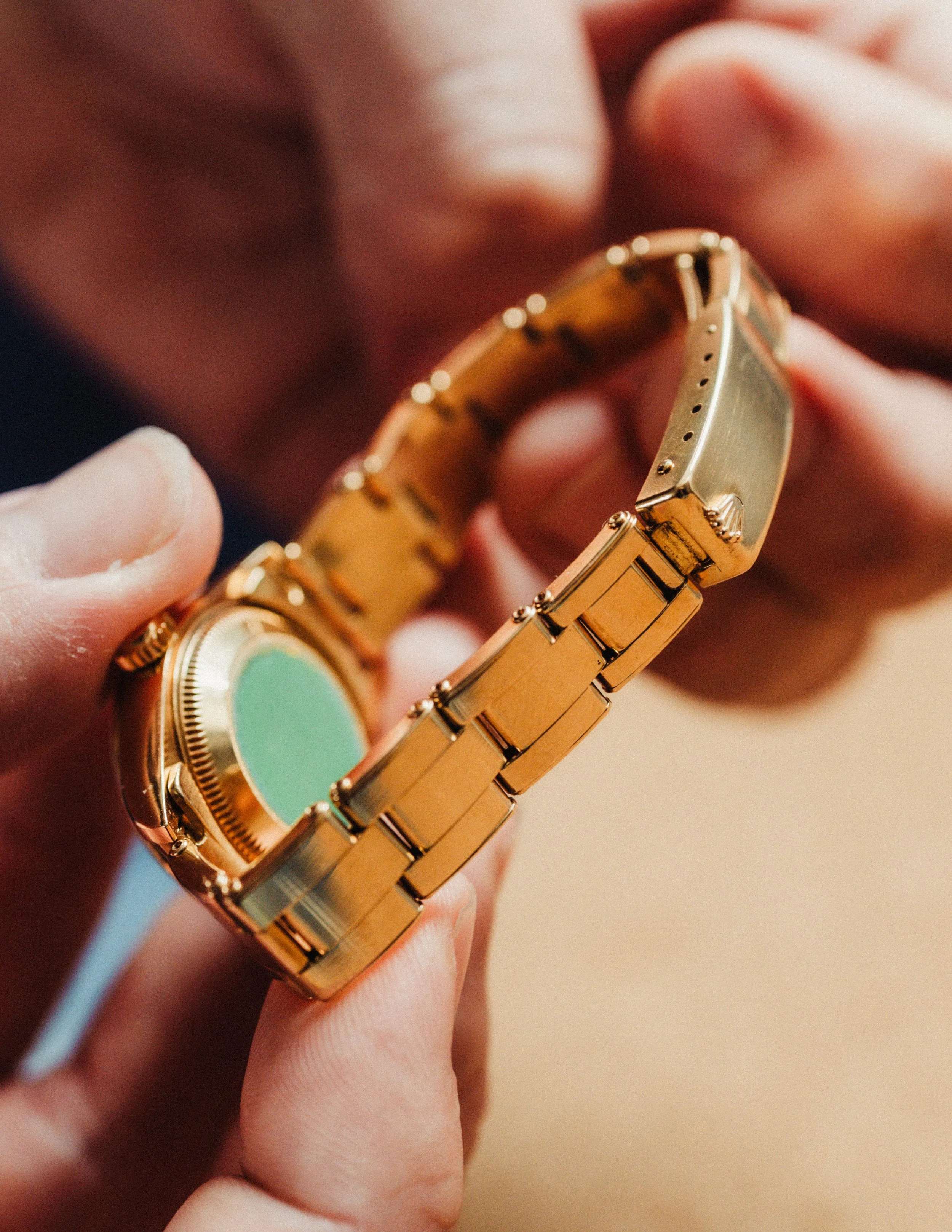 Close-up of a person holding a gold Ladies Rolex Datejust Wrist watch, focusing on the watch's Gold Riveted Bracelet and part of the face.
