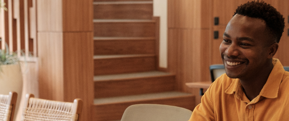 A man smiling in a modern wooden interior space.
