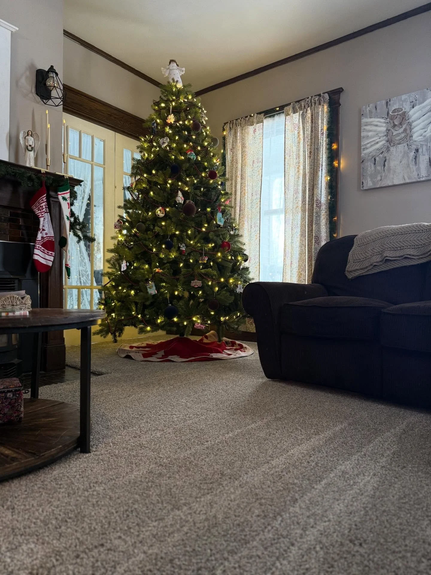Decorated Christmas tree with lights and ornaments in a cozy living room.