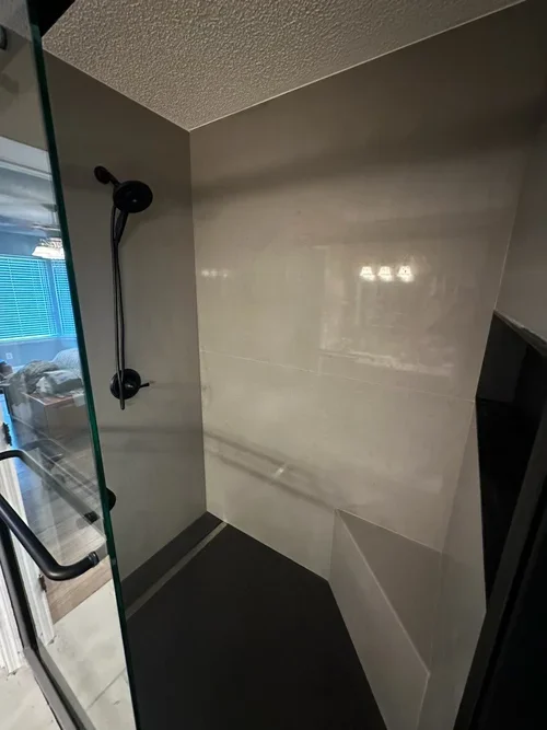 Modern gray seamless porcelain shower with black fixtures and zero grout lines installed in Michigan