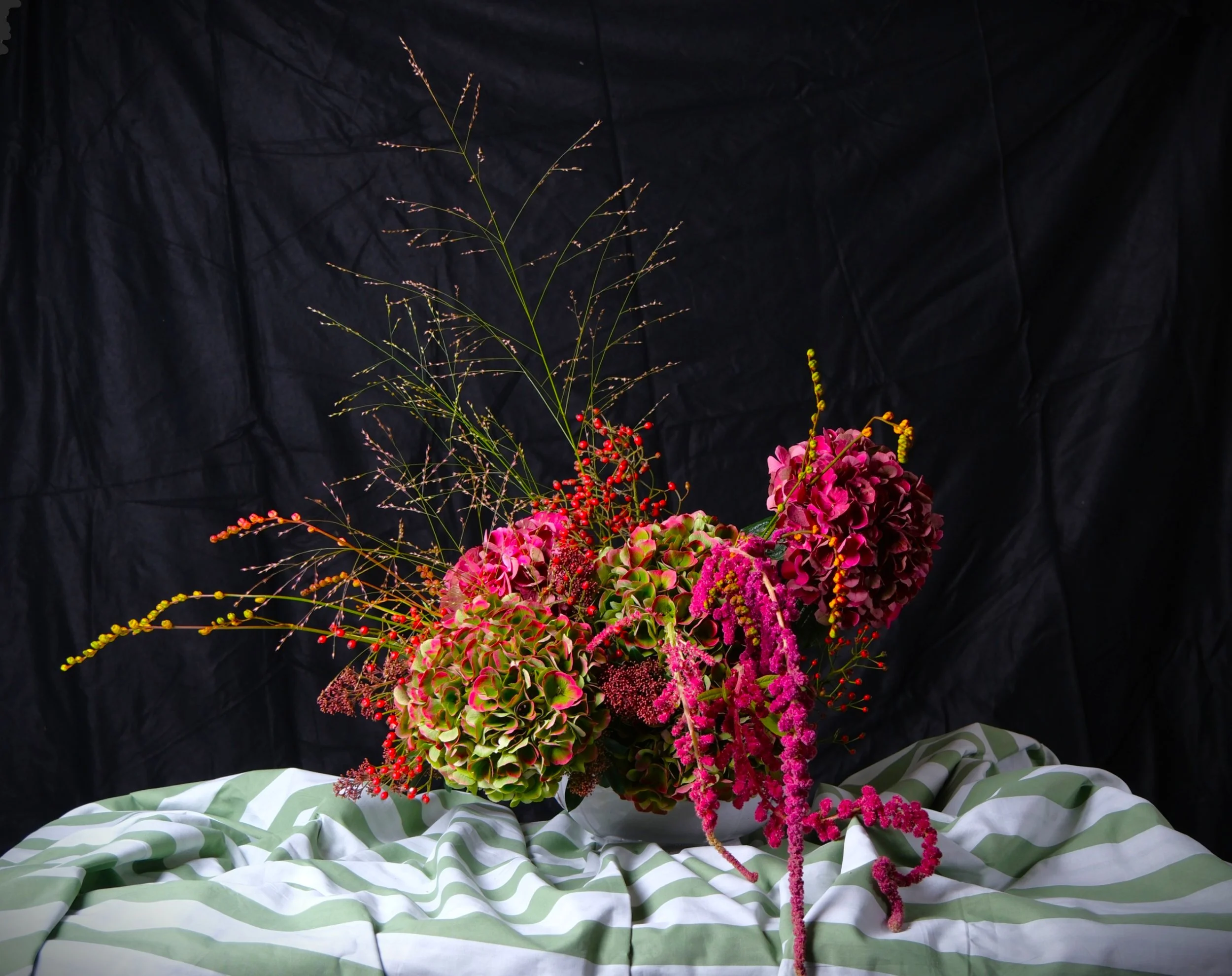 A moody, sultry modern floral arrangement with mottled hydrangea, red amaranthus and grasses.