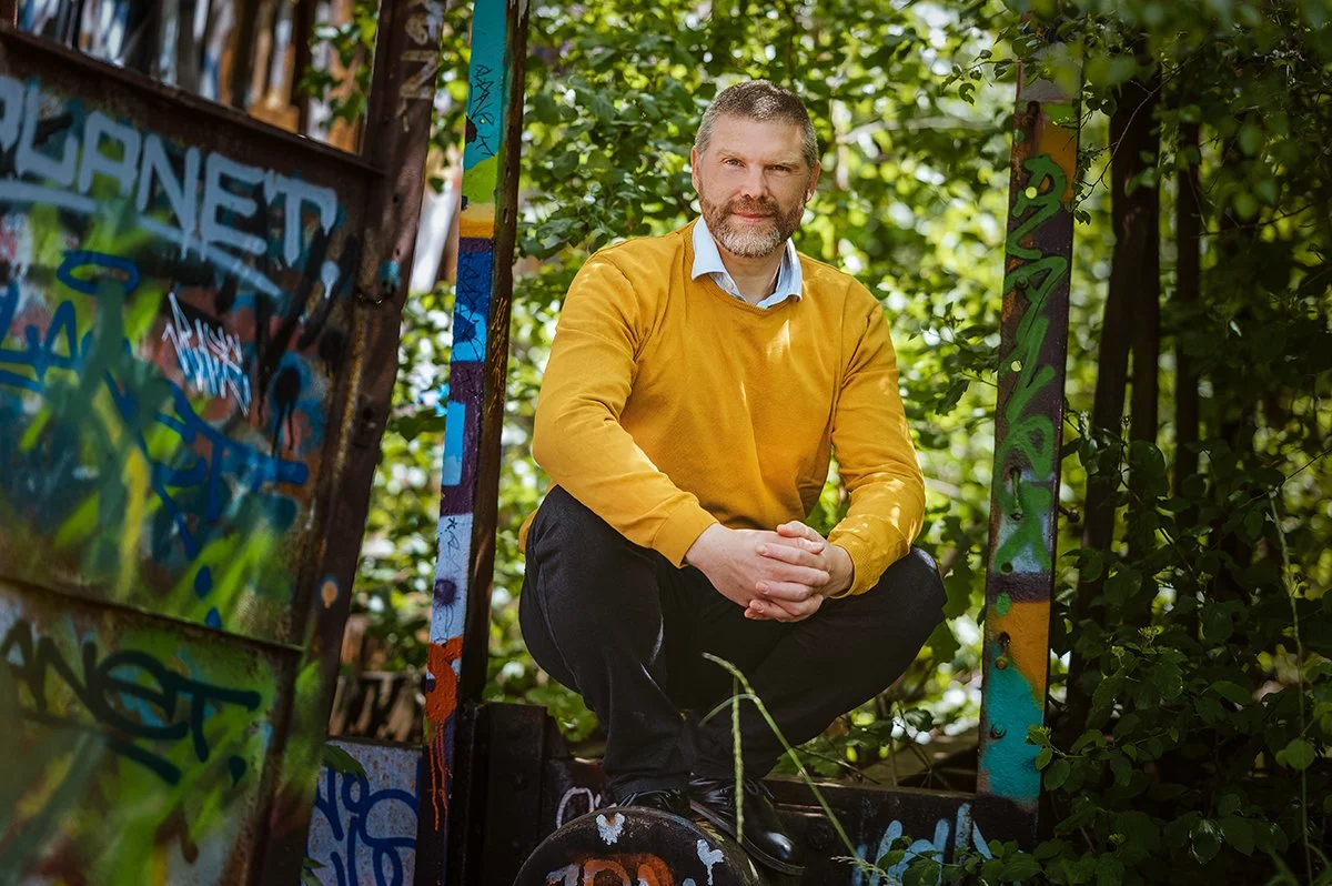 Mann während Fotoshooting im Wald hockend