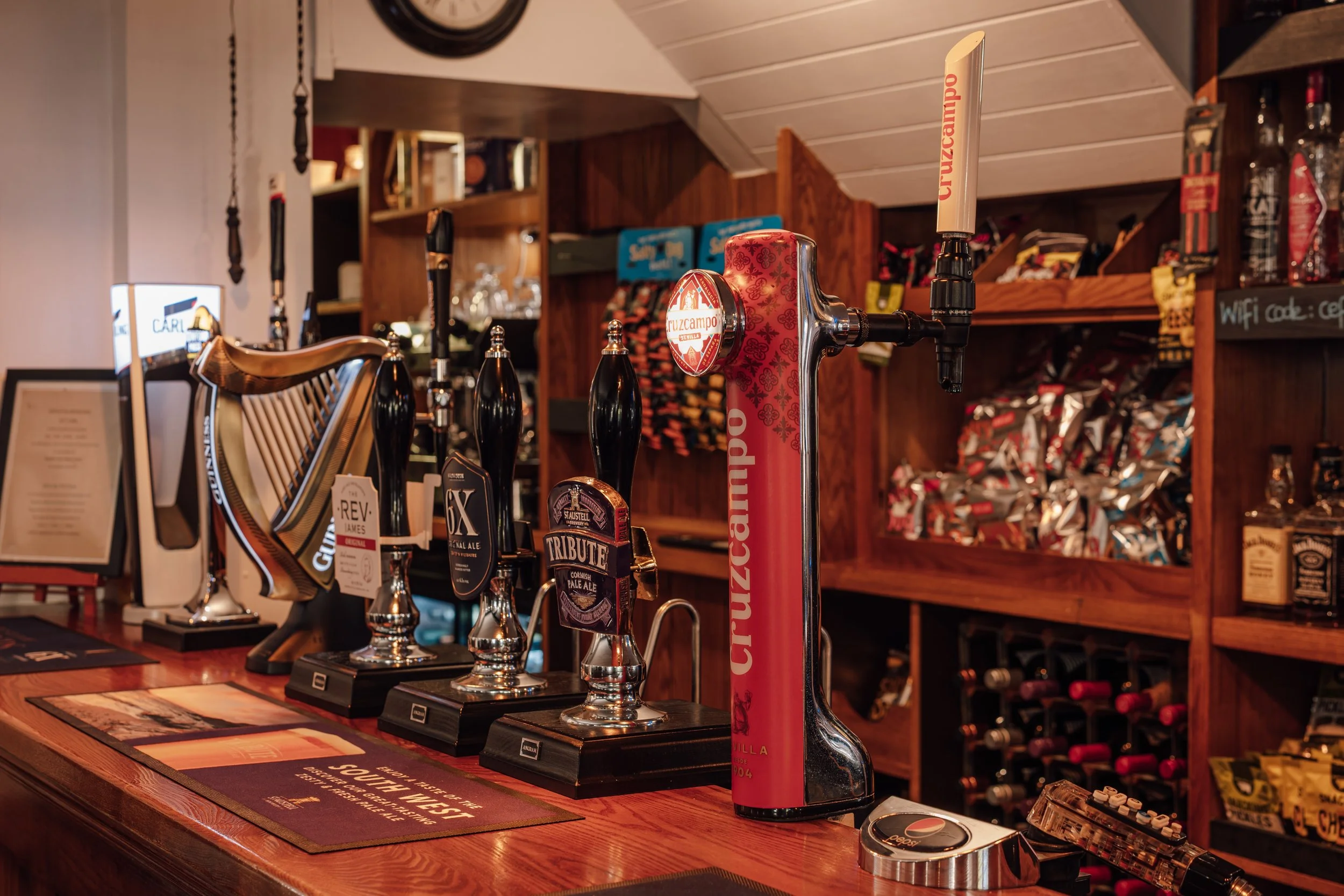 Bar counter with beer taps and assorted snacks in a cozy pub or restaurant.