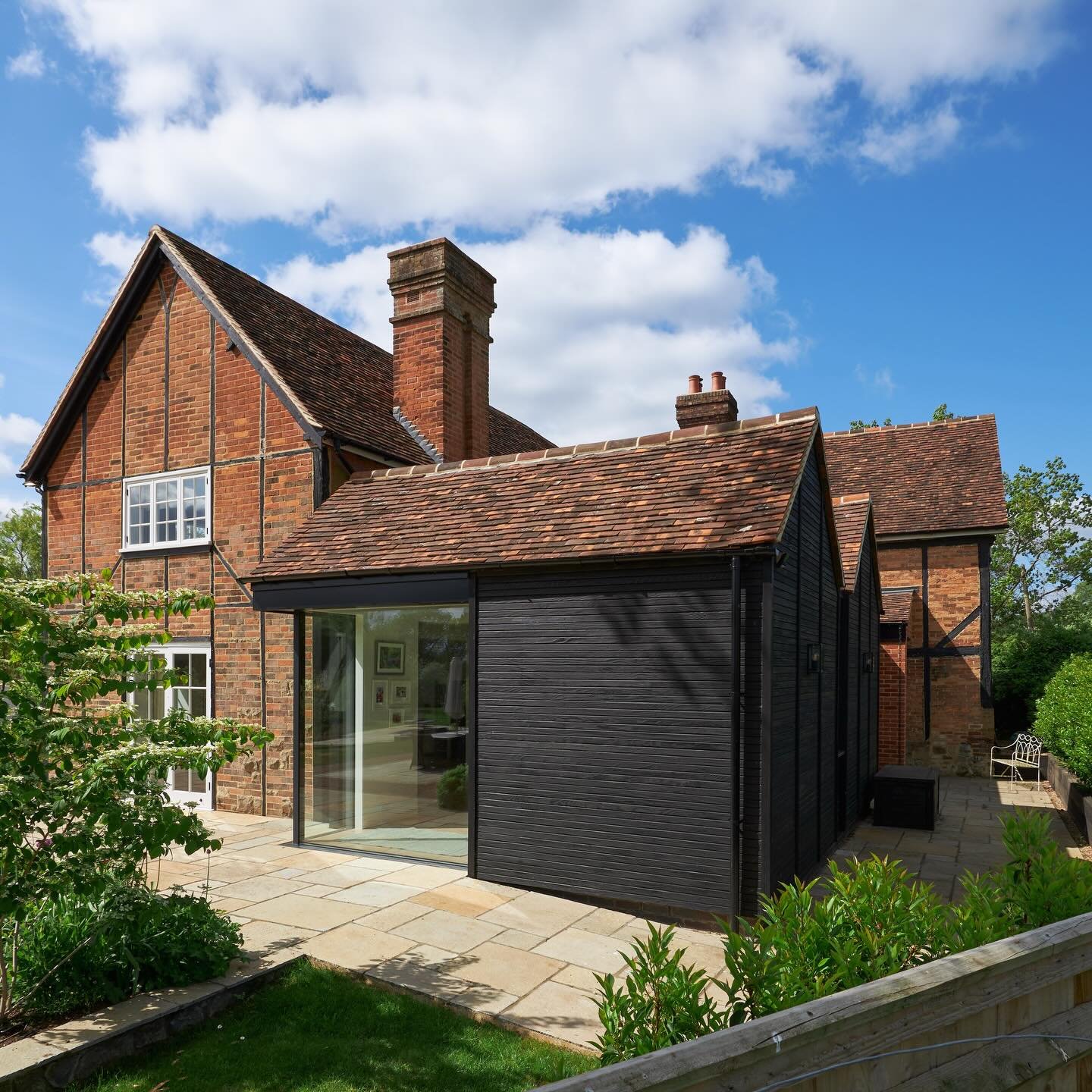 A considered addition to this Grade II Listed country house.

Black charred cladding and carefully judged proportions draw on both heritage and contemporary influences, allowing the new form to sit comfortably alongside the original red brick fabric 