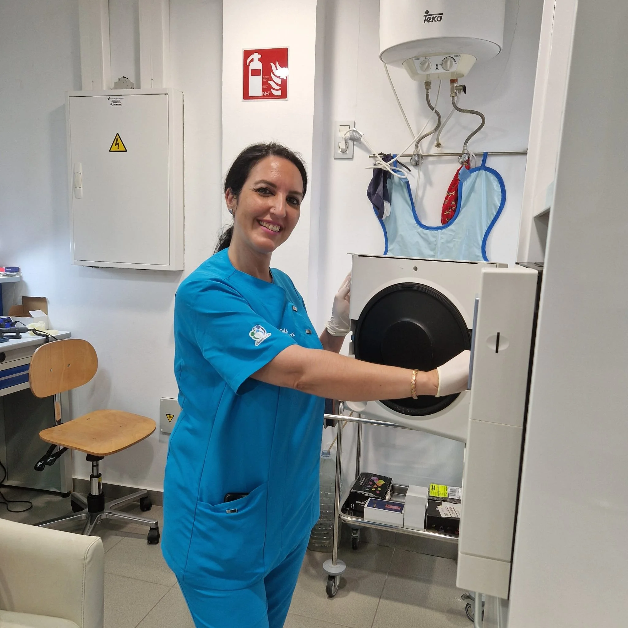 Una infermiera sorridente in divisa azzurra apre una macchina diagnostica in una clinica o ospedale.