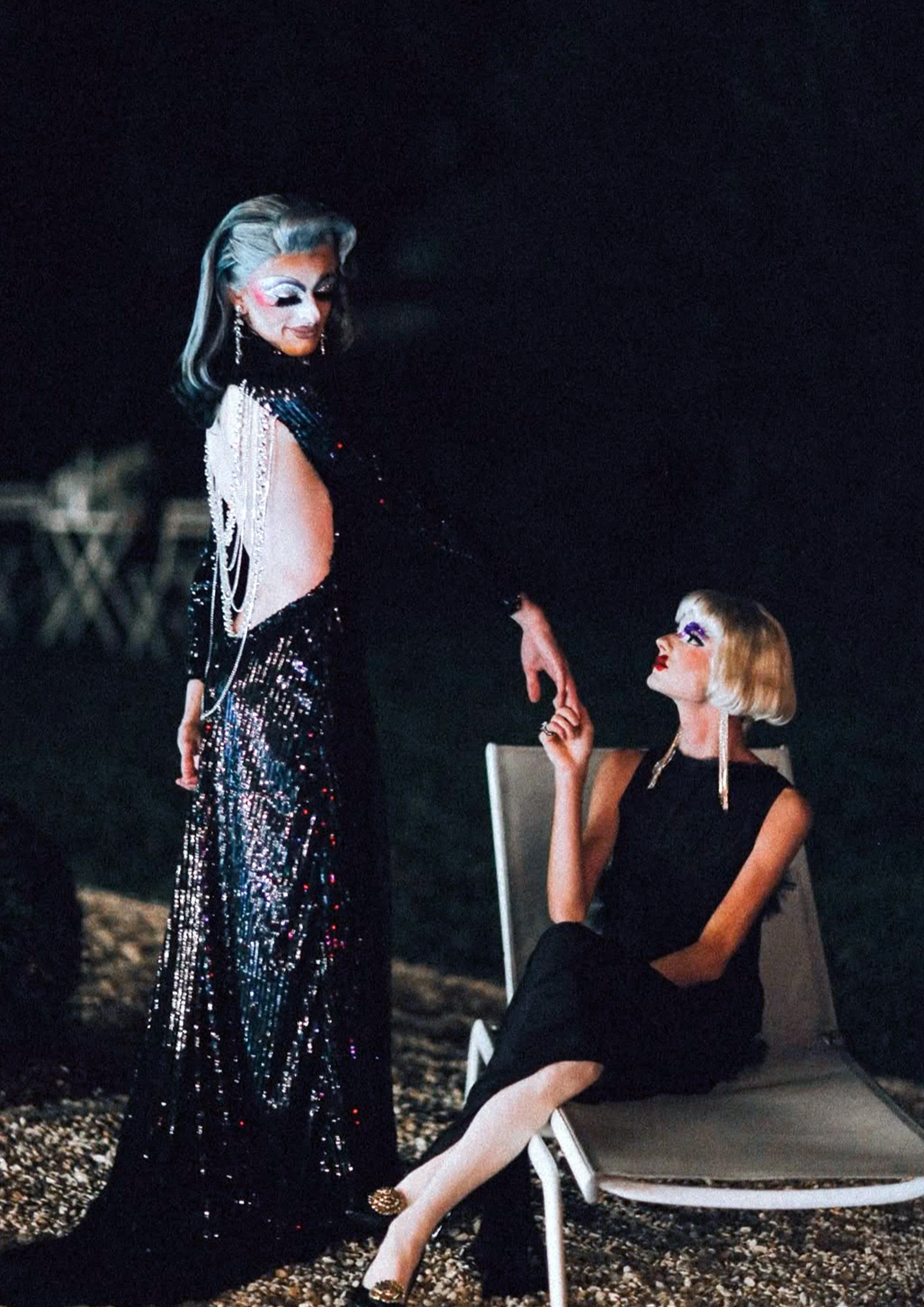Les artistes drag Gala et Bichon de la troupe La Nuit Drag dans une scène élégante en extérieur, Gala portant une robe de soirée noire à paillettes et Bichon une robe noire assise.