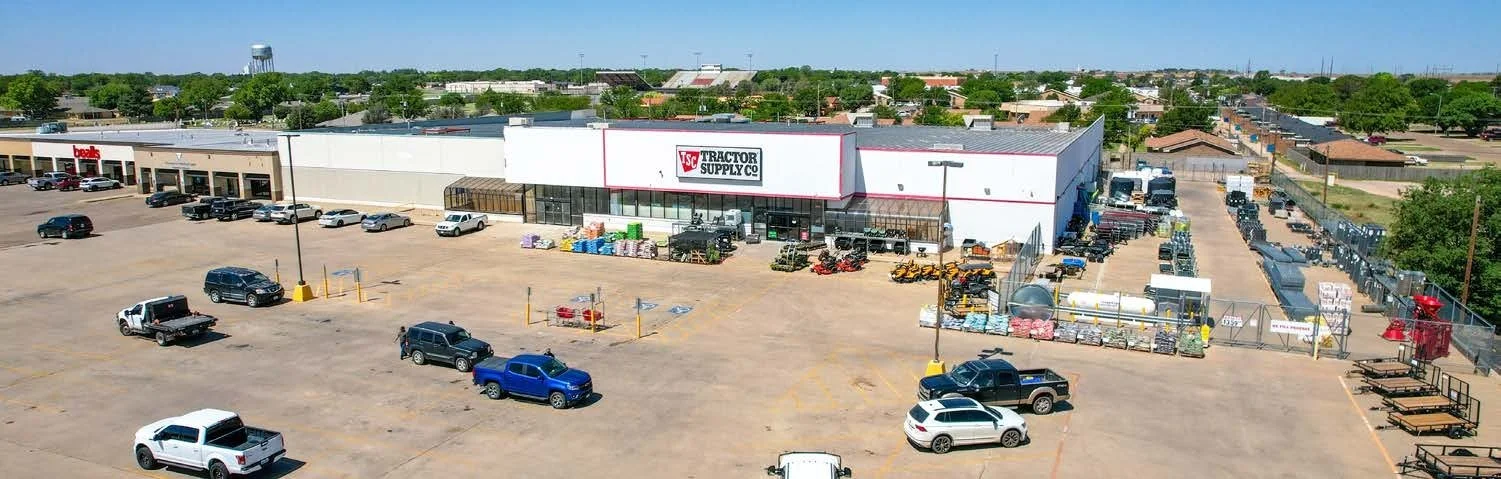 A large retail store in a parking lot with multiple cars parked and an array of supplies outside, viewed from above.