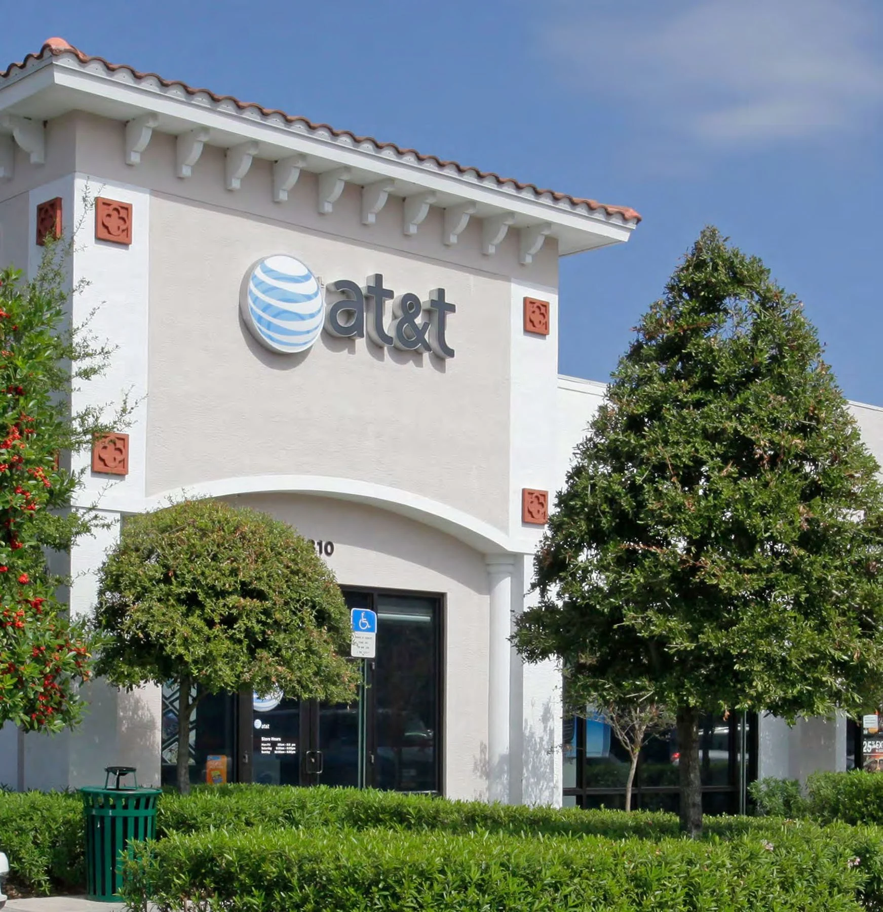AT&T store with trees and bushes in front and a blue sky overhead.