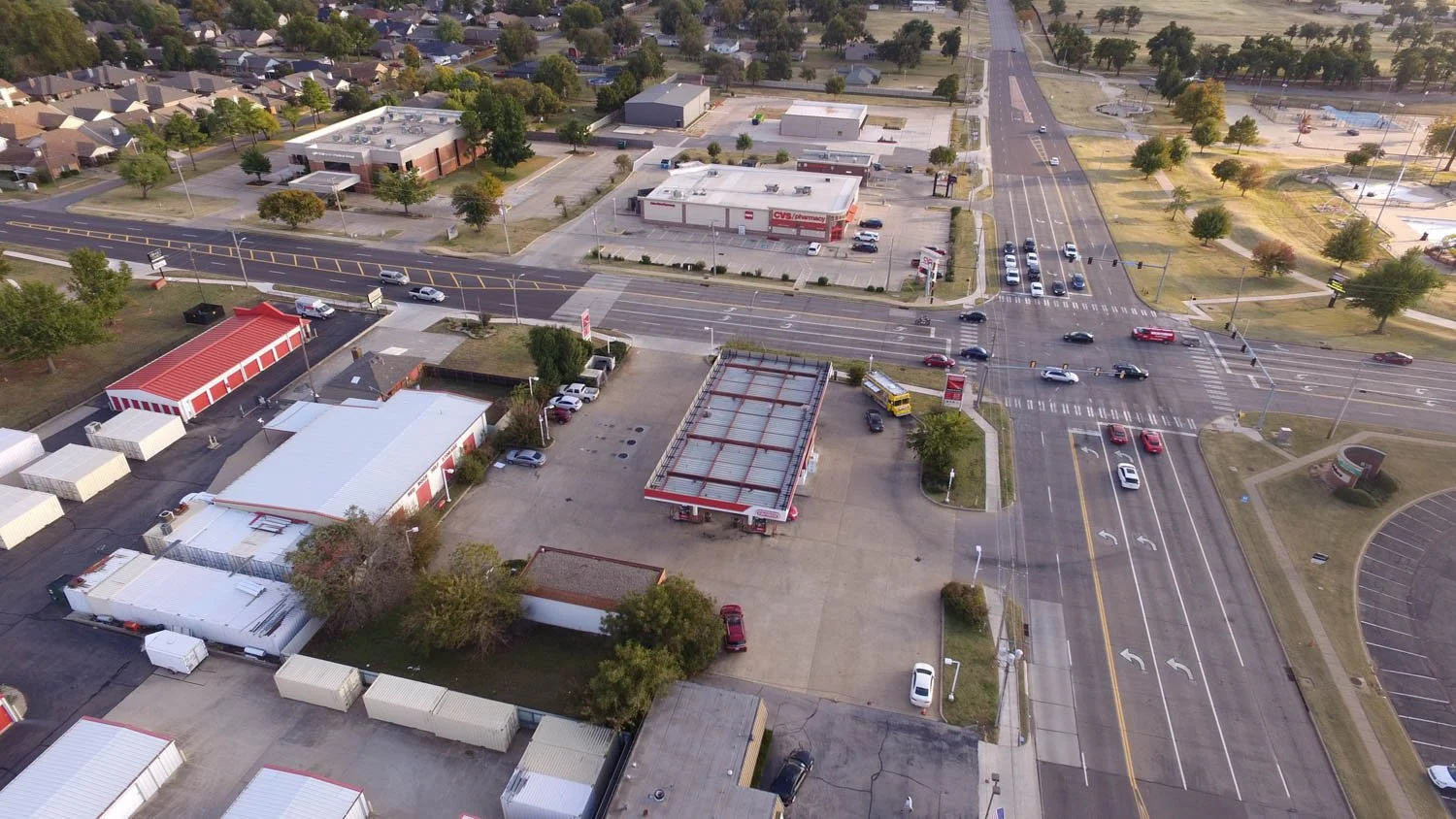 An aerial view of a commercial area featuring a CVS pharmacy, an adjacent parking lot, and surrounding roads with cars.