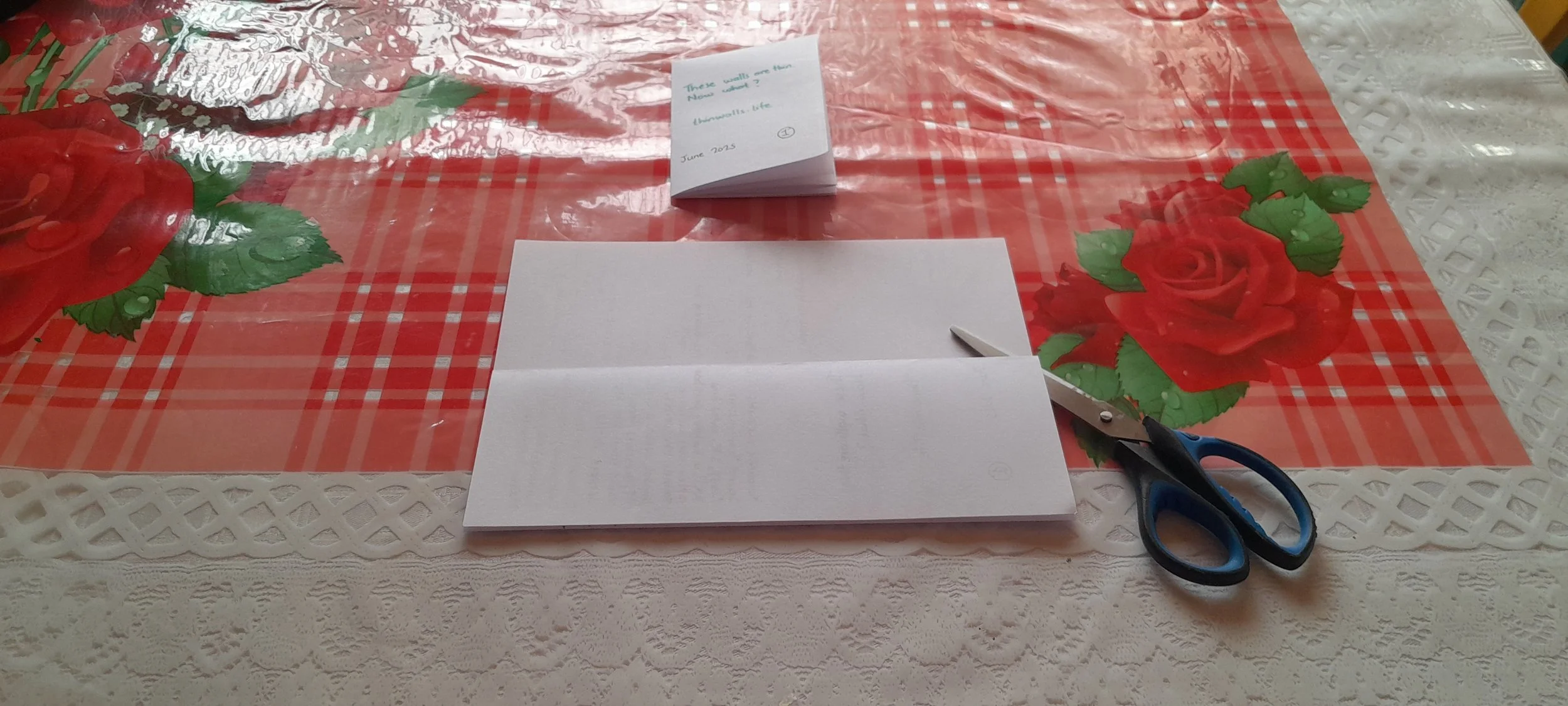 Paper folded multiple times width-wise, showing three vertical creases for the zine layout.