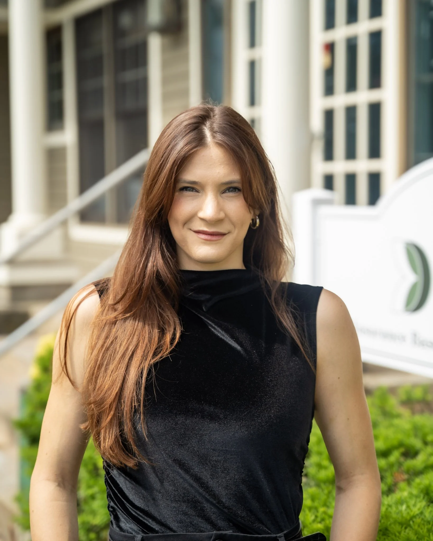 Professional headshot of nutritionist Monica Marcello standing outside in front of greenery and a white building.