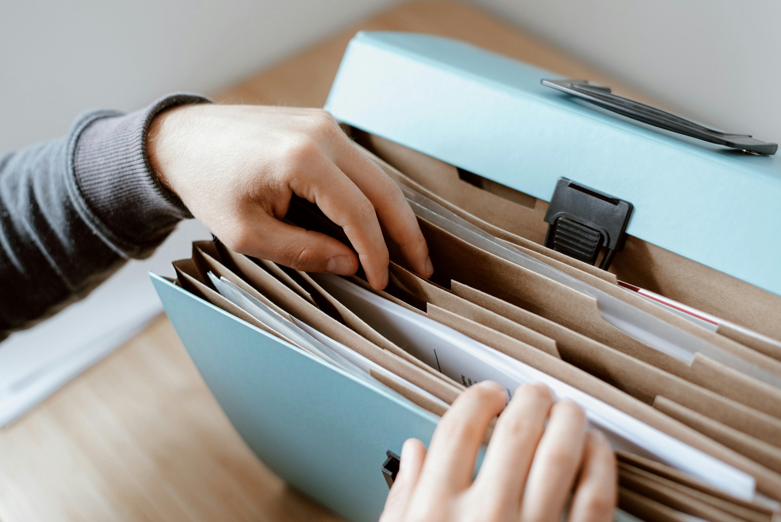 A person organizing documents in a blue file box with folders and papers inside to symbolize the EMDR Therapy process.