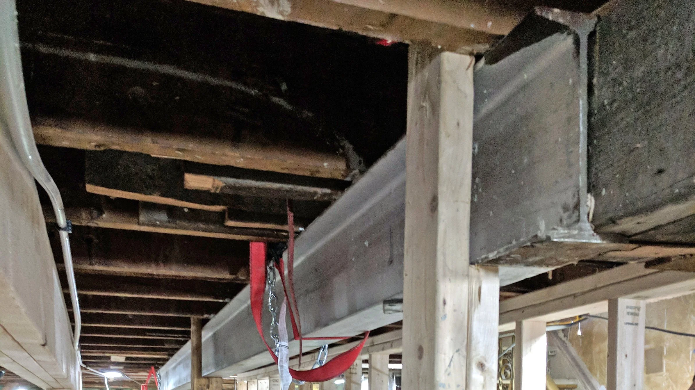 Construction site with exposed wooden beams and ductwork installed underneath a floor.