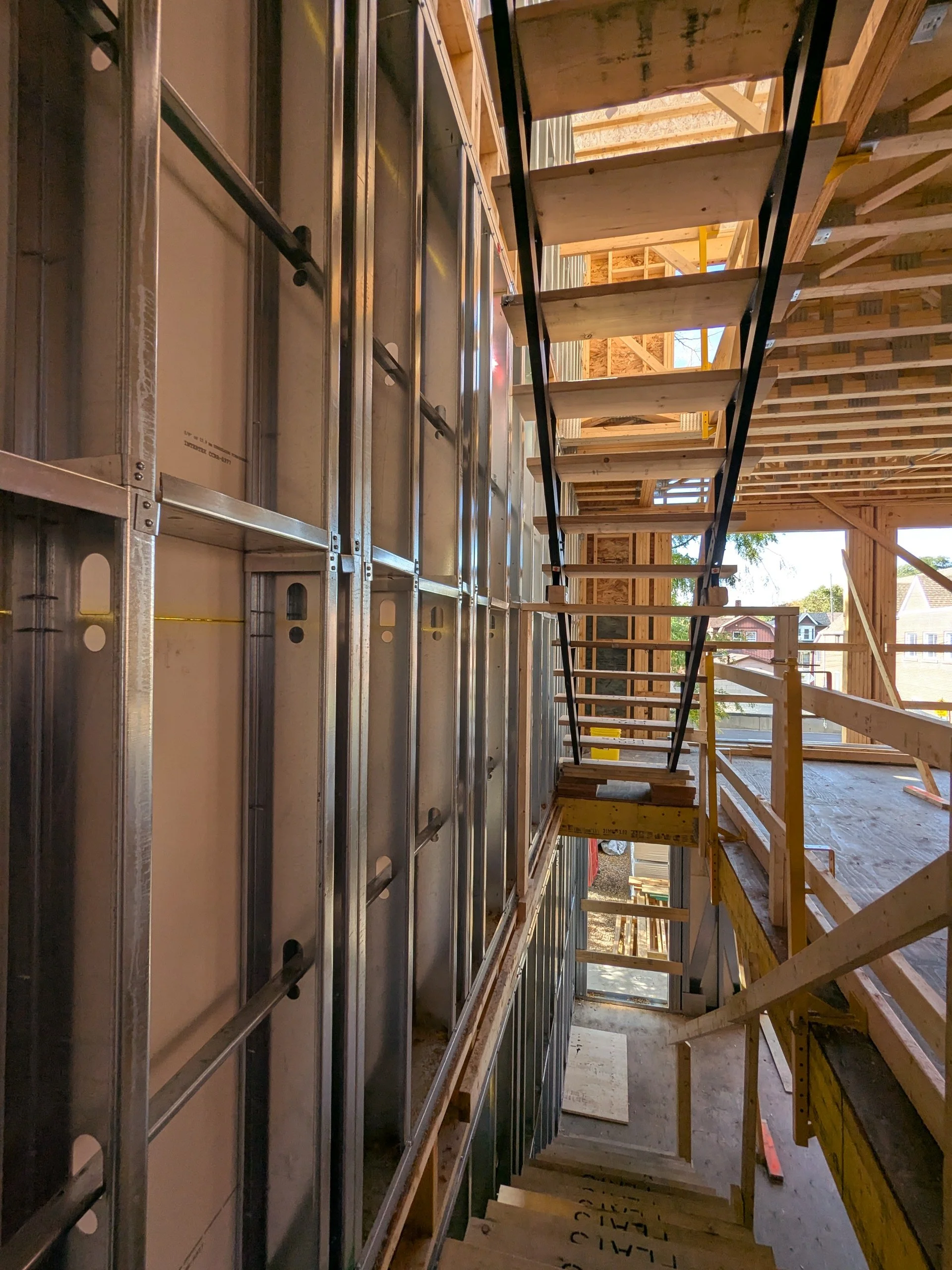 Construction site with a wooden staircase and metal framing in a partially built structure.