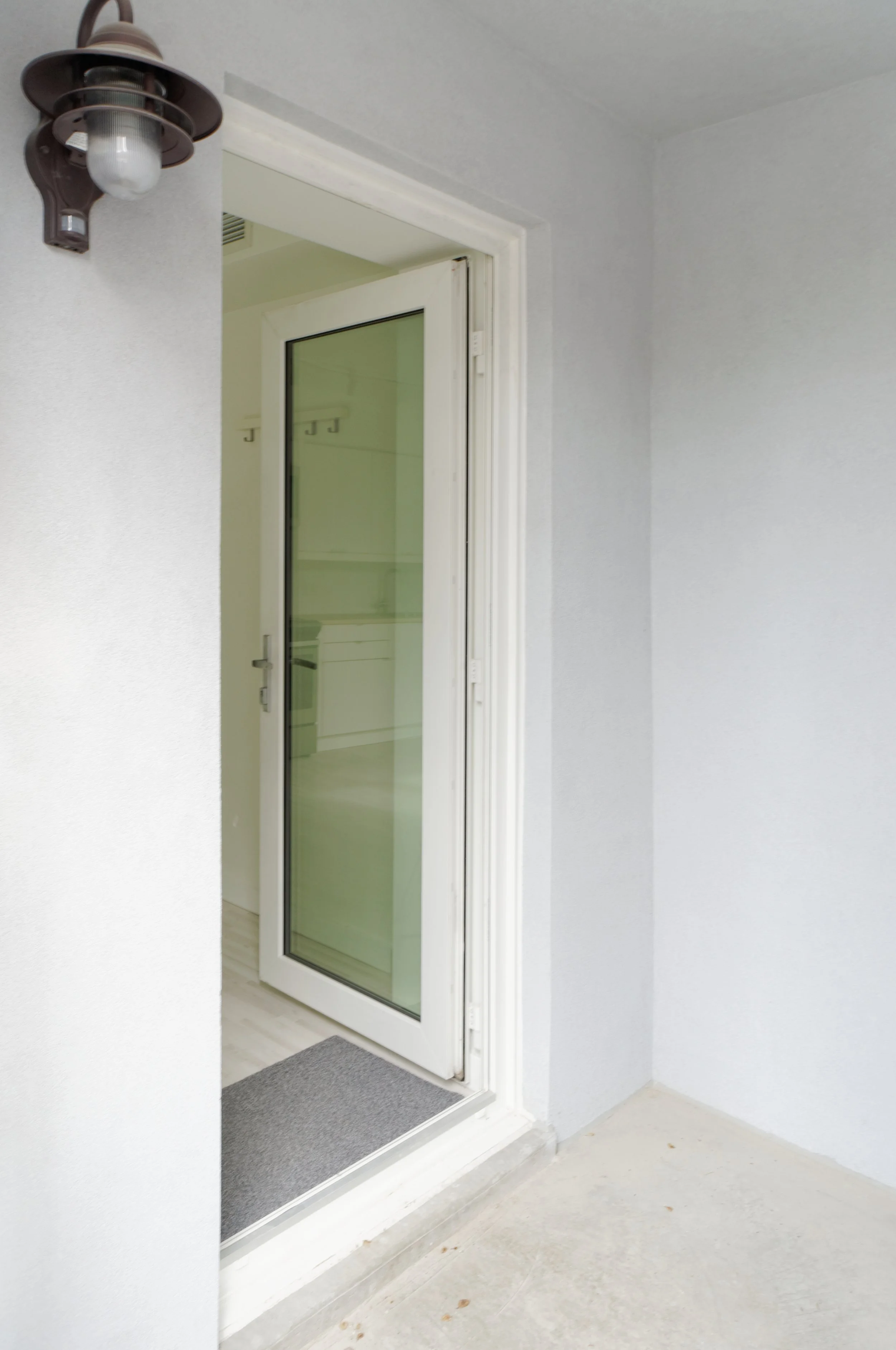 Entrance with a glass door and wall-mounted outdoor light fixture.
