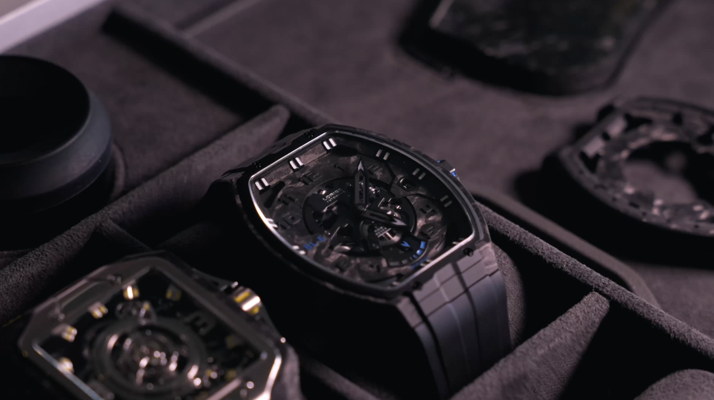 A luxury wristwatch with a skeleton dial showing its inner mechanisms, placed in a watch box with other watch components nearby.