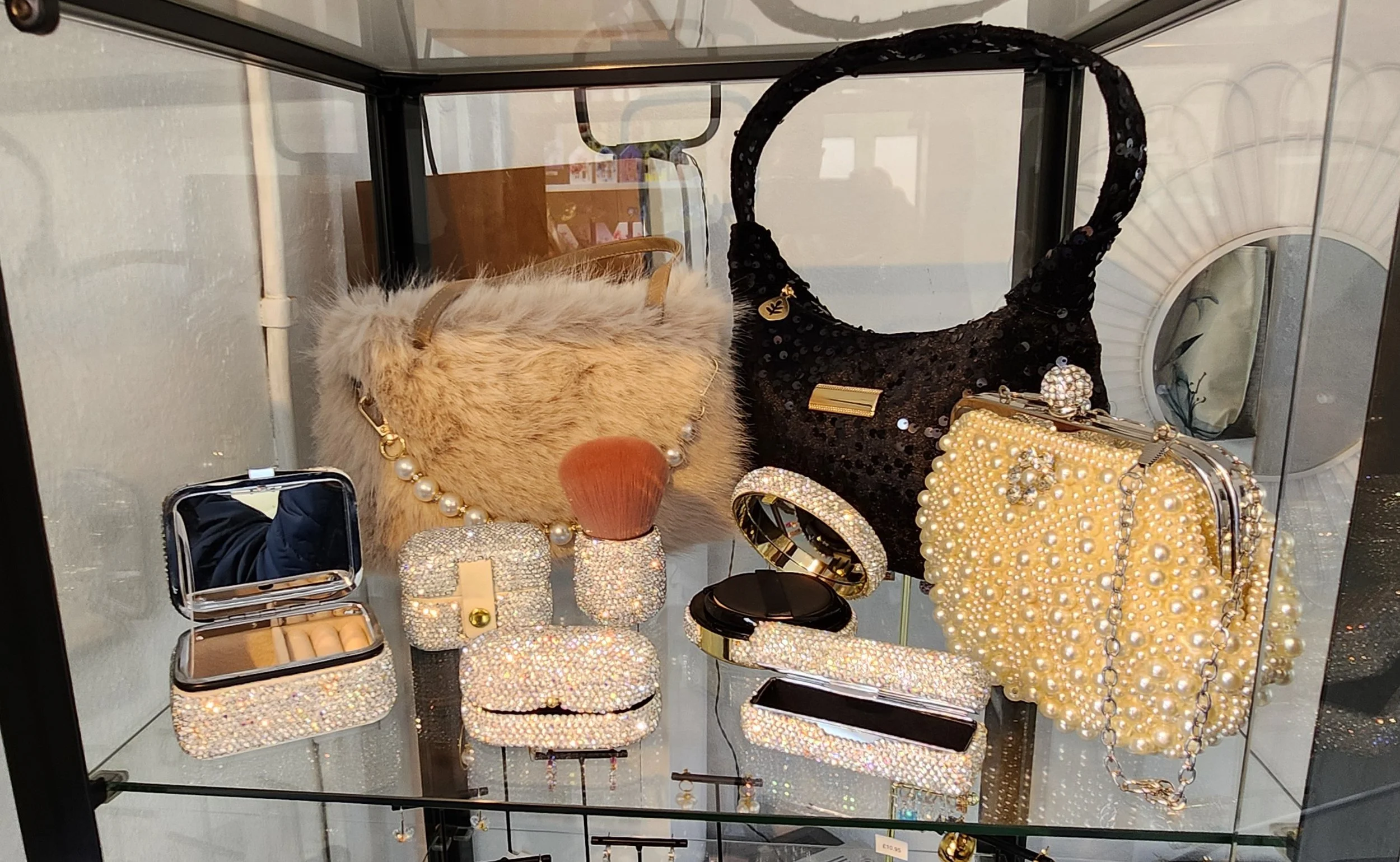 Display case with various bejeweled accessories including handbags, jewelry and jewelry boxes.