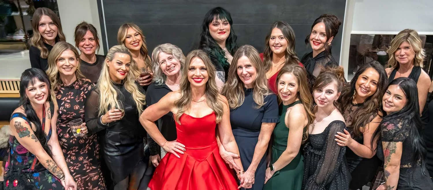 Group of women at a celebration or party, smiling and posing for the photo, some holding drinks.