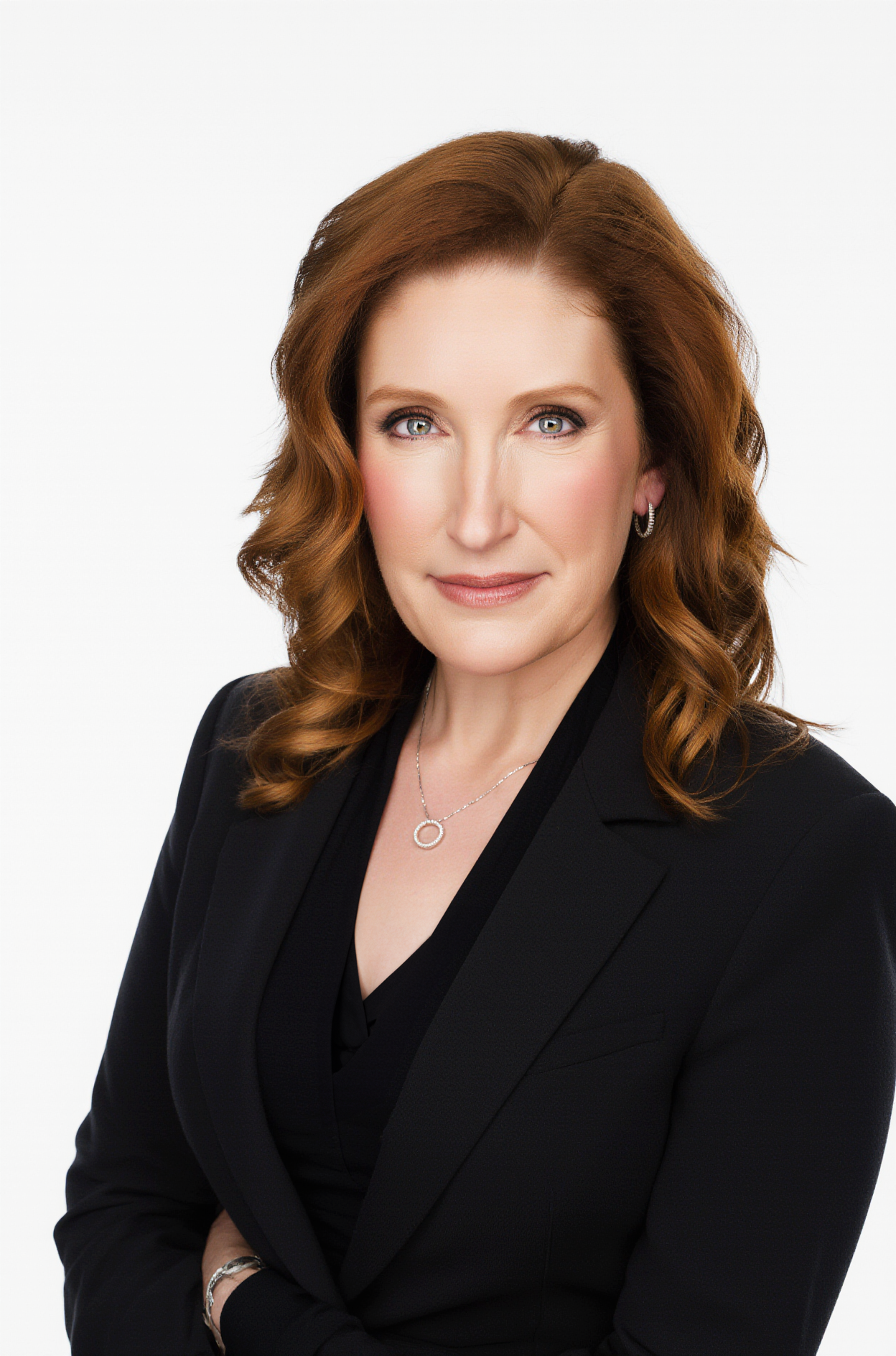 Tissa Richards wearing a black blazer and jewelry against a white background.