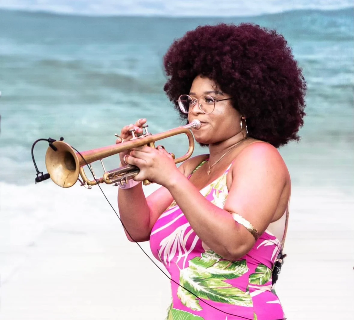 Tatiana Tate playing trumpet on beach.