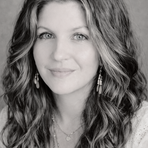 Black and white portrait of a woman with wavy hair, earrings, and a slight smile.