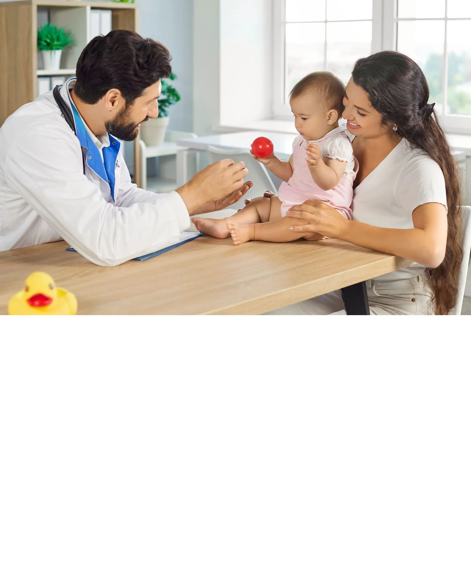 A woman holding a baby with a pink headband, viewed from behind