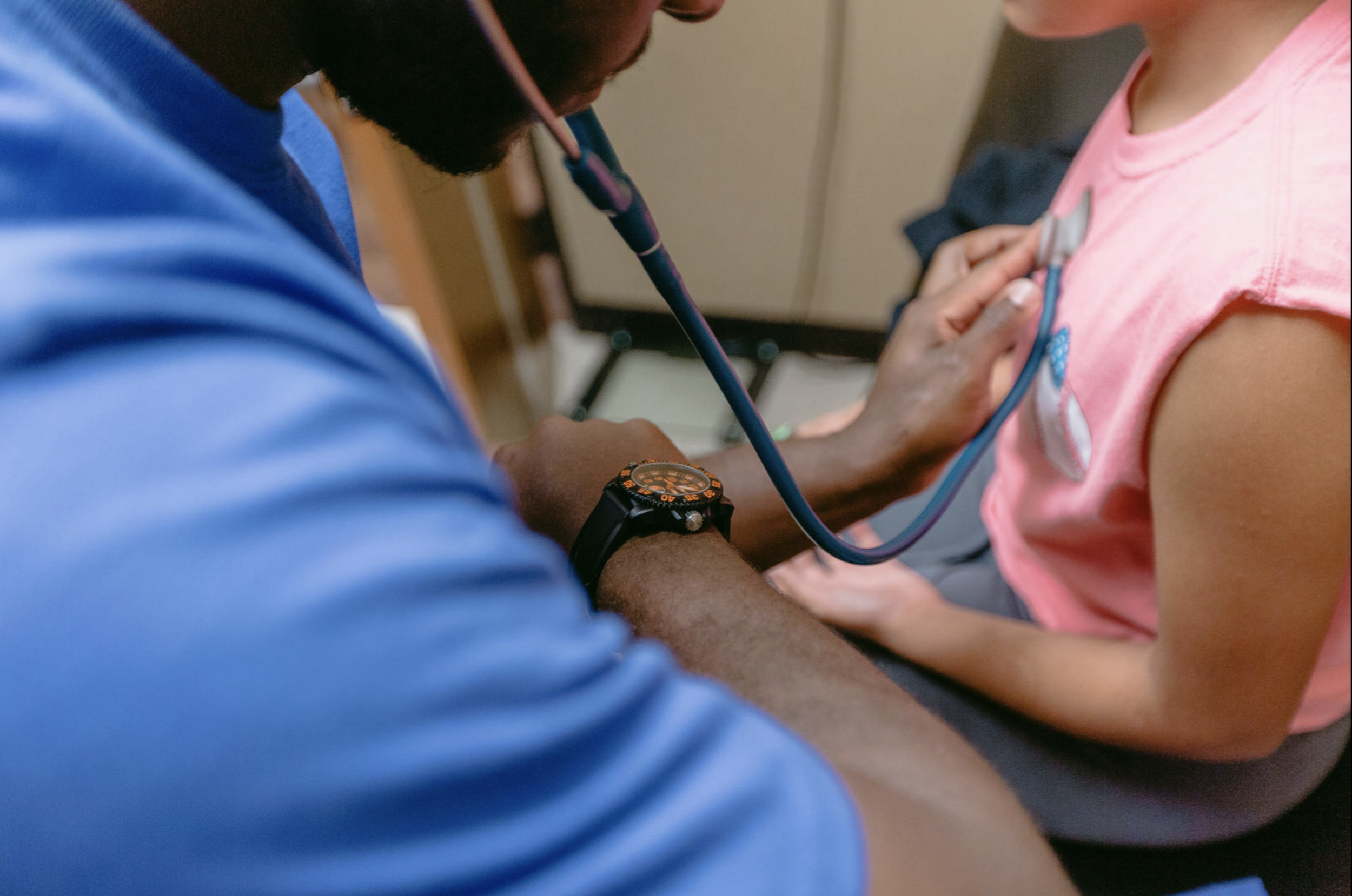 a pediatric healthcare provider using a stethoscope to check a child’s heartbeat