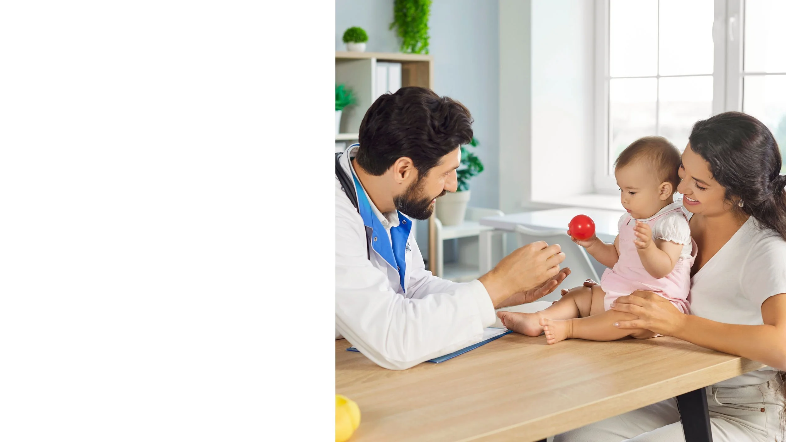 Person holding a baby's head in their hands, with the baby wearing a pink headband, indoors with natural light.
