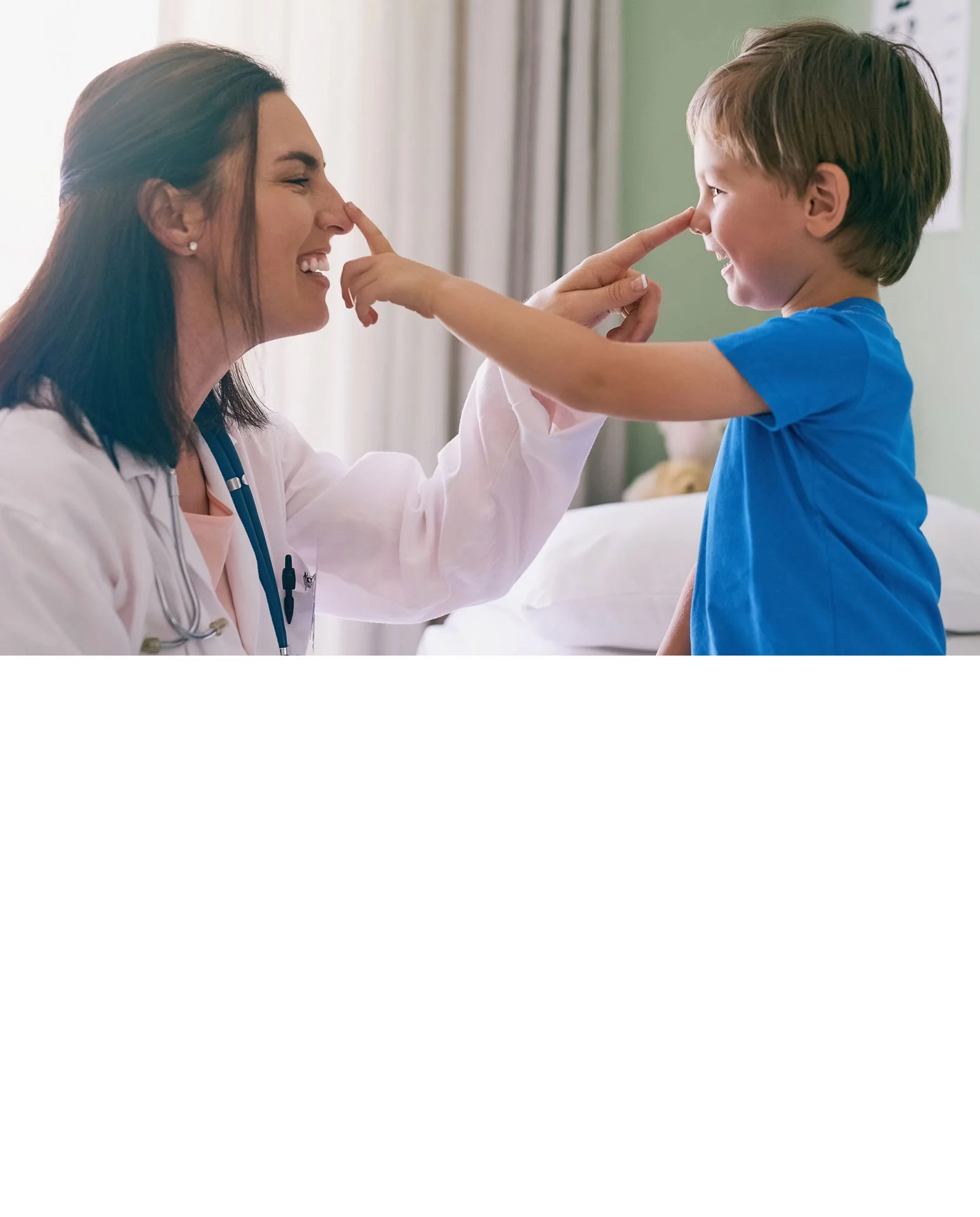 A doctor examining a young child with a stethoscope while the child is sitting on an adult's lap in an examination room.